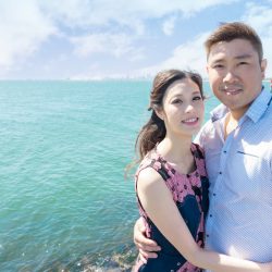 four season engagement photo of young Hong Kong couple standing in front of blue ocean in sunny day