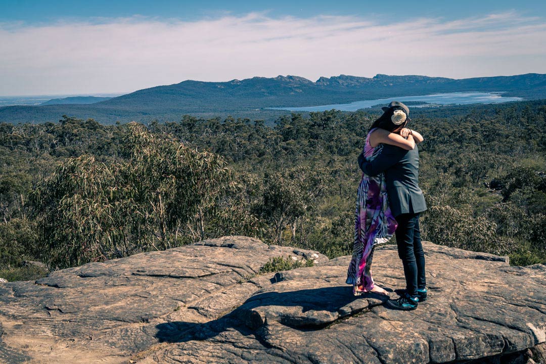 happy newly engaged couple hugged for a long time at Reeds look out the Grampians in Australia during their surprise proposal photography by Black Avenue Productions