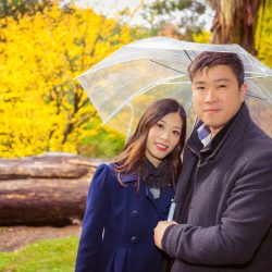 boyfriend and girlfriend holding umbrella under the rain for their engagement photography