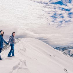 award winning image of engaged couple climbing up the top of a snow mountain in Falls Creek Victoria Australia by Black Avenue Productions