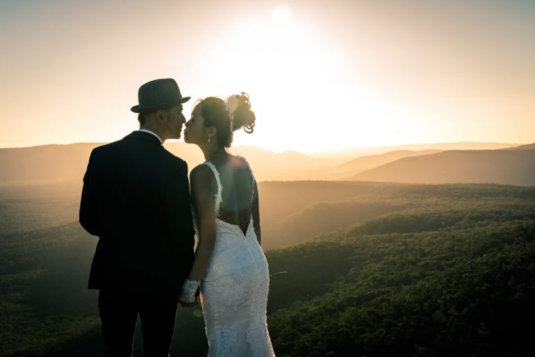 bride groom kissing in front of stunning sunset view on The Grampians hilltop