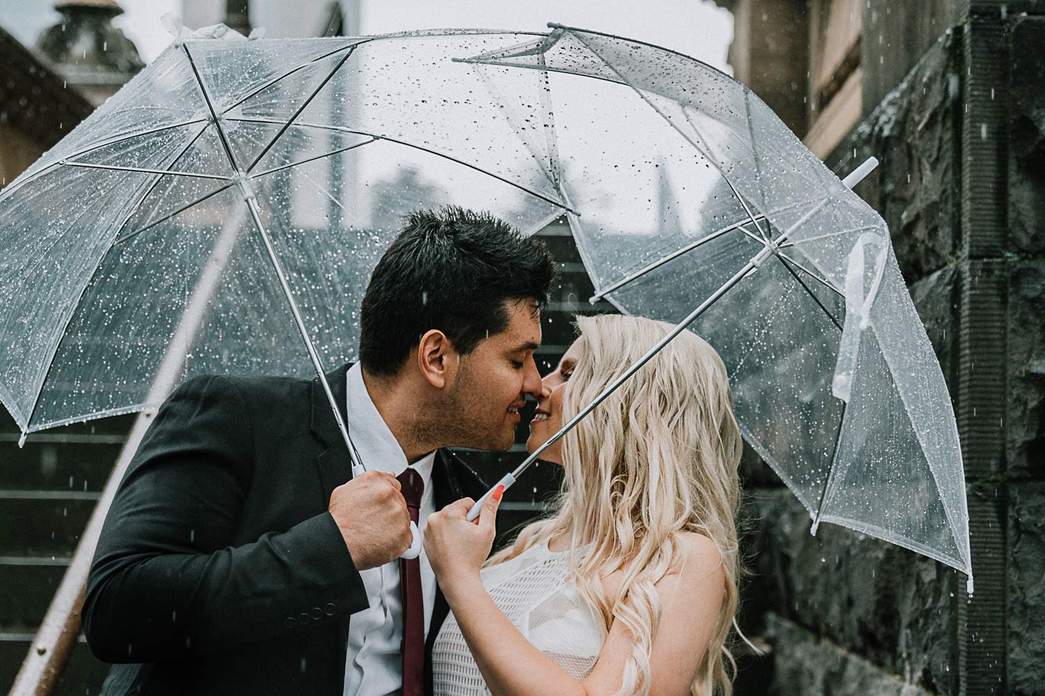 Melbourne couple holding clear umbrellas during a rainy day for pre wedding photo shoot