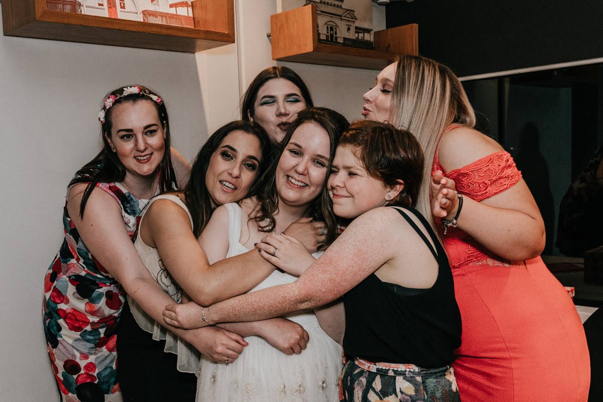 girls hug to celebrate friendship forever during best friend Melbourne wedding reception in Little Blue kiosk in St Kilda beach Melbourne