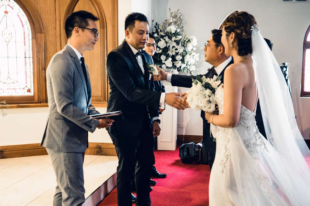 the moment that father hand bride to groom in church wedding capture by Black Avenue Productions