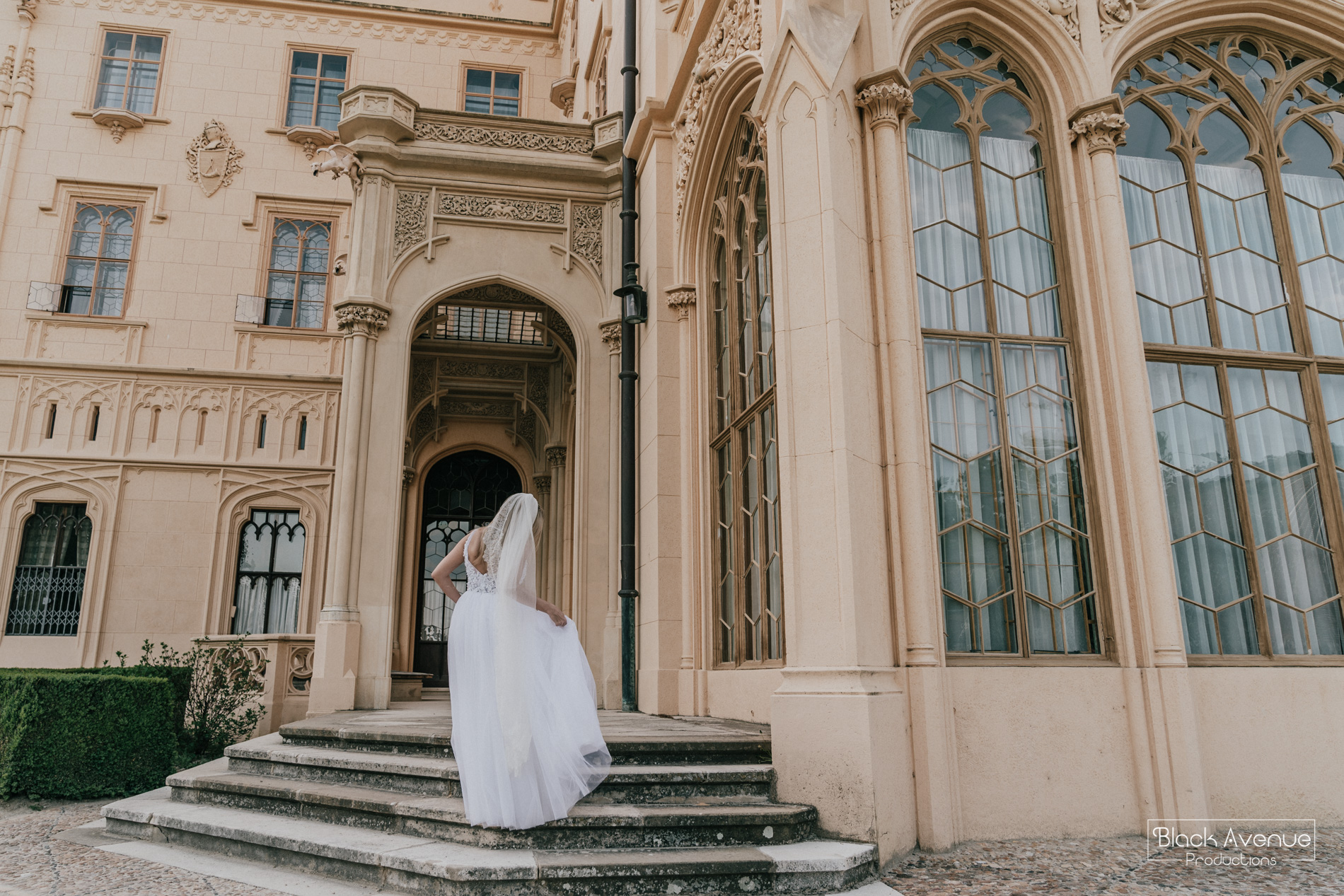 image of the back of a stunning bride in Leah S Design bridal dress running to a castle captured by destination wedding photographer Derek Chan and Lowina Blackman