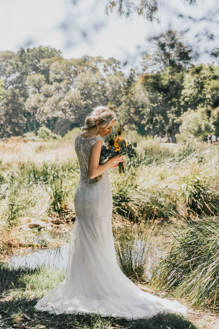 beautiful elegant bride smell kiss flowers bouquets in bush grass pond and shrub