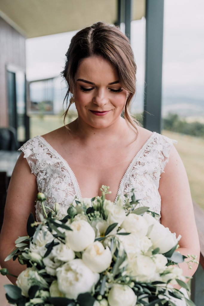 bride wearing a white gown holding white bouquet of roses