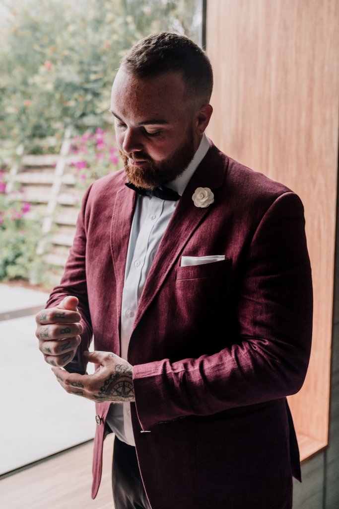 groom fixing his maroon suit by menzclub