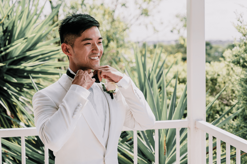 asian groom wearing white tuxedo in a magical city wedding in melbourne photo by black avenue productions
