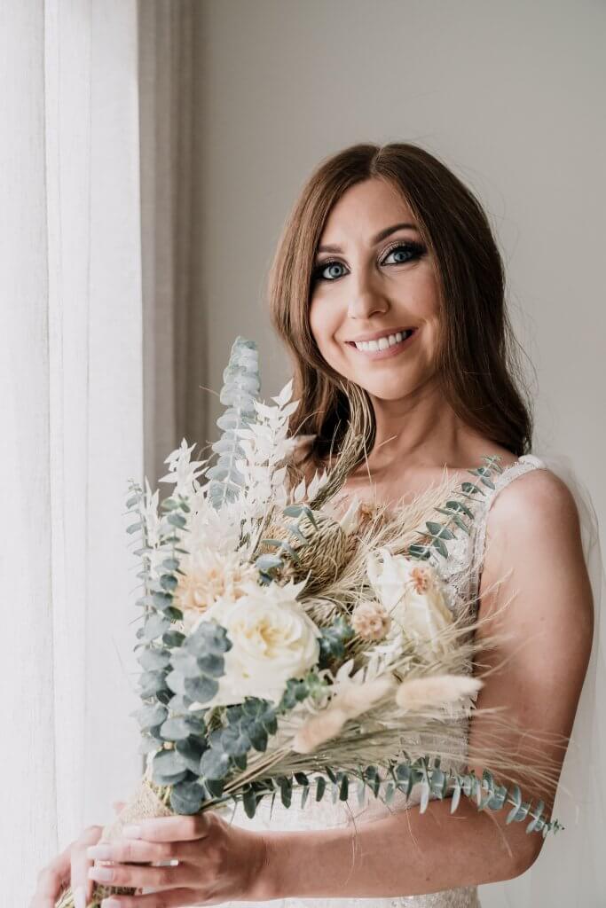 bride smiling while holding a bouquet flowers, captured by Black Avenue Productions
