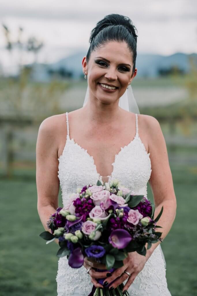 Lovely bride holding a bouquet of mixed violet and pink flowers, captured by Black Avenue Productions