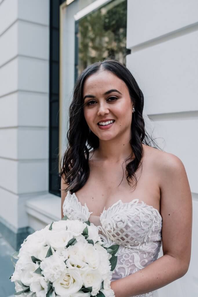 Lovely bride holding a beautiful bouquet by the street, captured by Black Avenue Productions