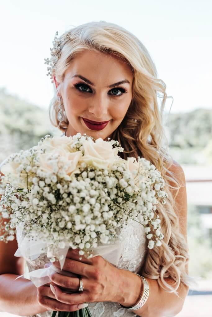 Beautiful bride holding a bouquet of white flowers, captured by Black Avenue Productions