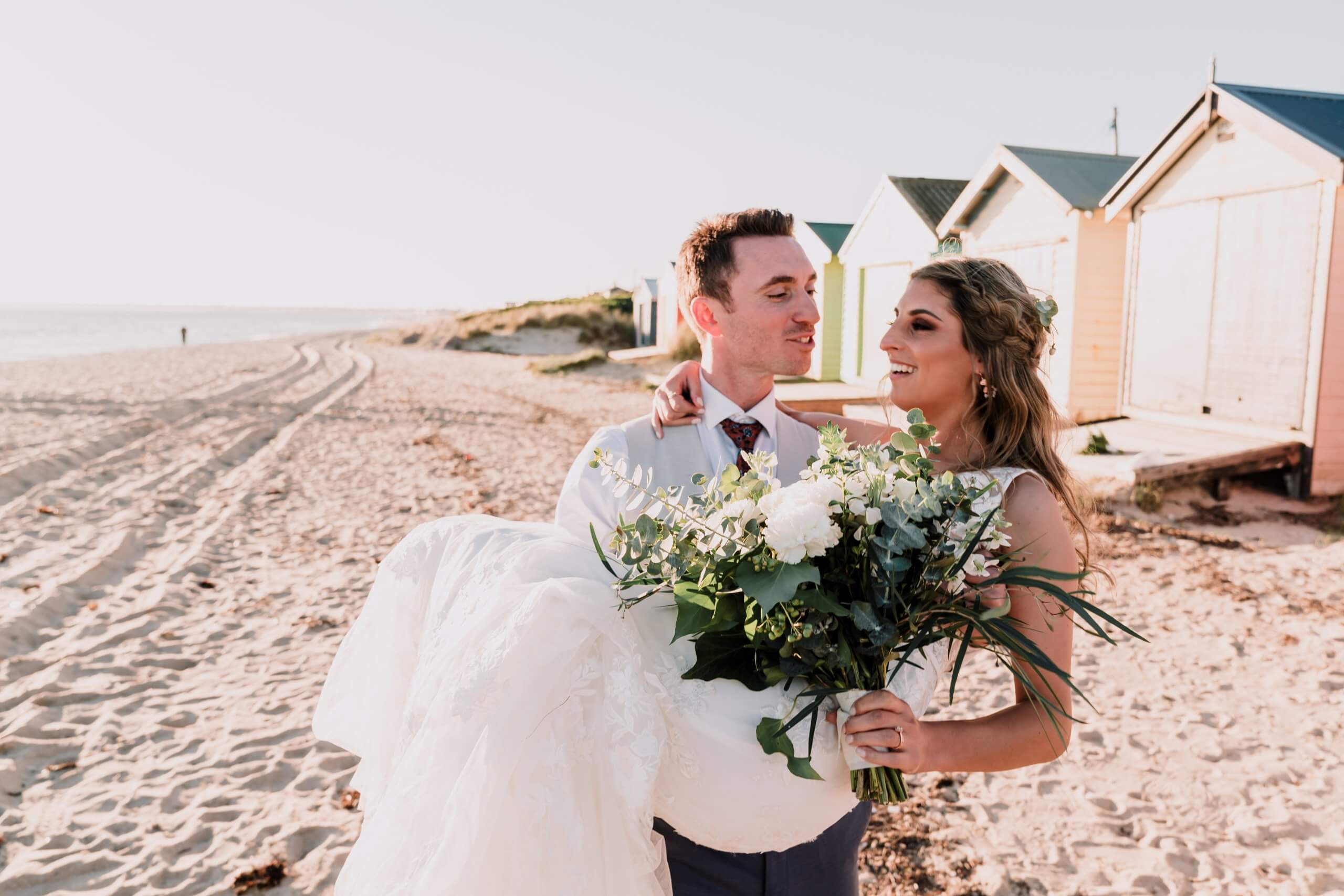 Husband carrying her bride by the beach, captured by black avenue productions