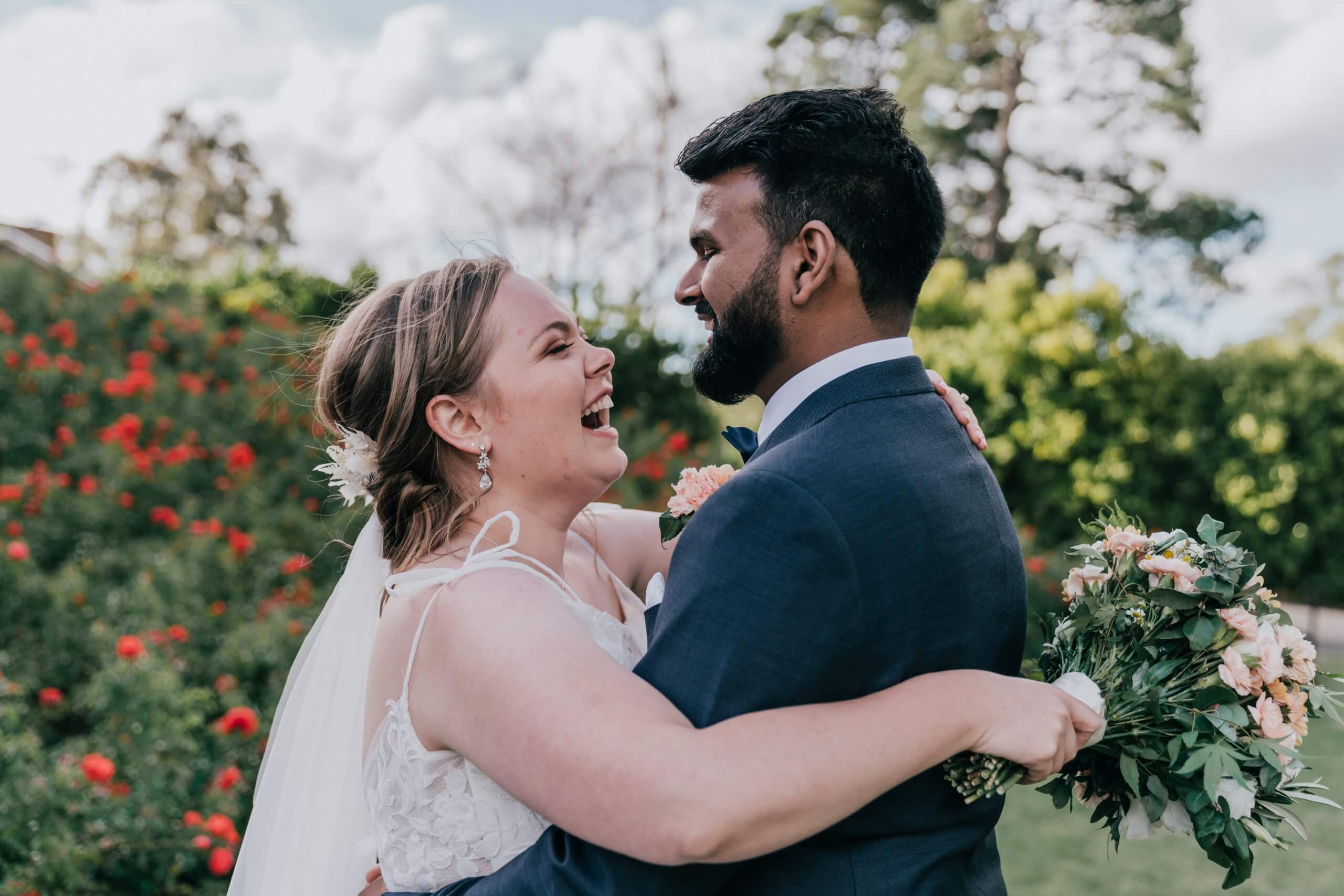 Bride and Groom happily hugging each other by a beautiful garden, Captured by Black Avenue Productions