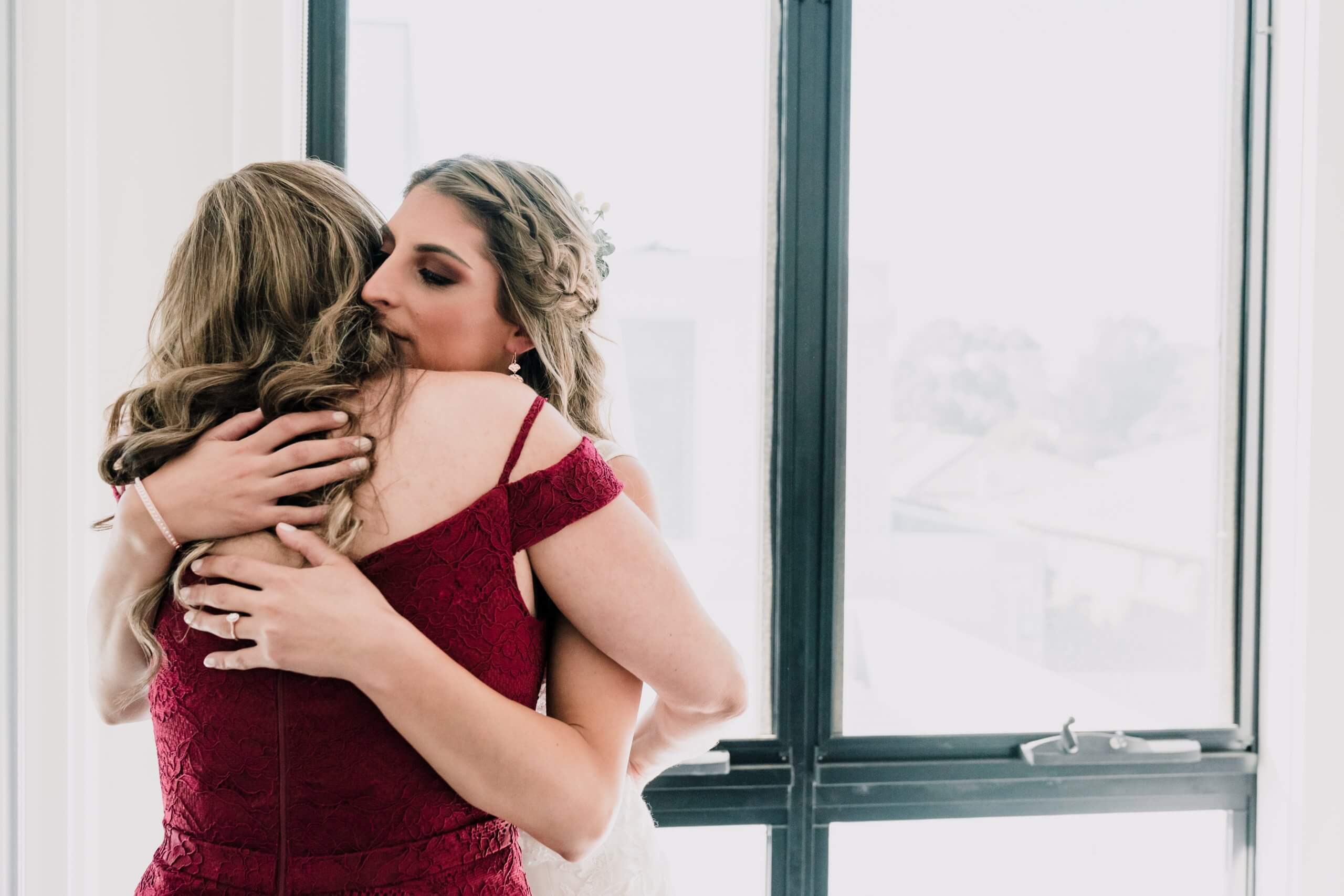 The bride hugging her bridesmaid captured by Black Avenue Productions