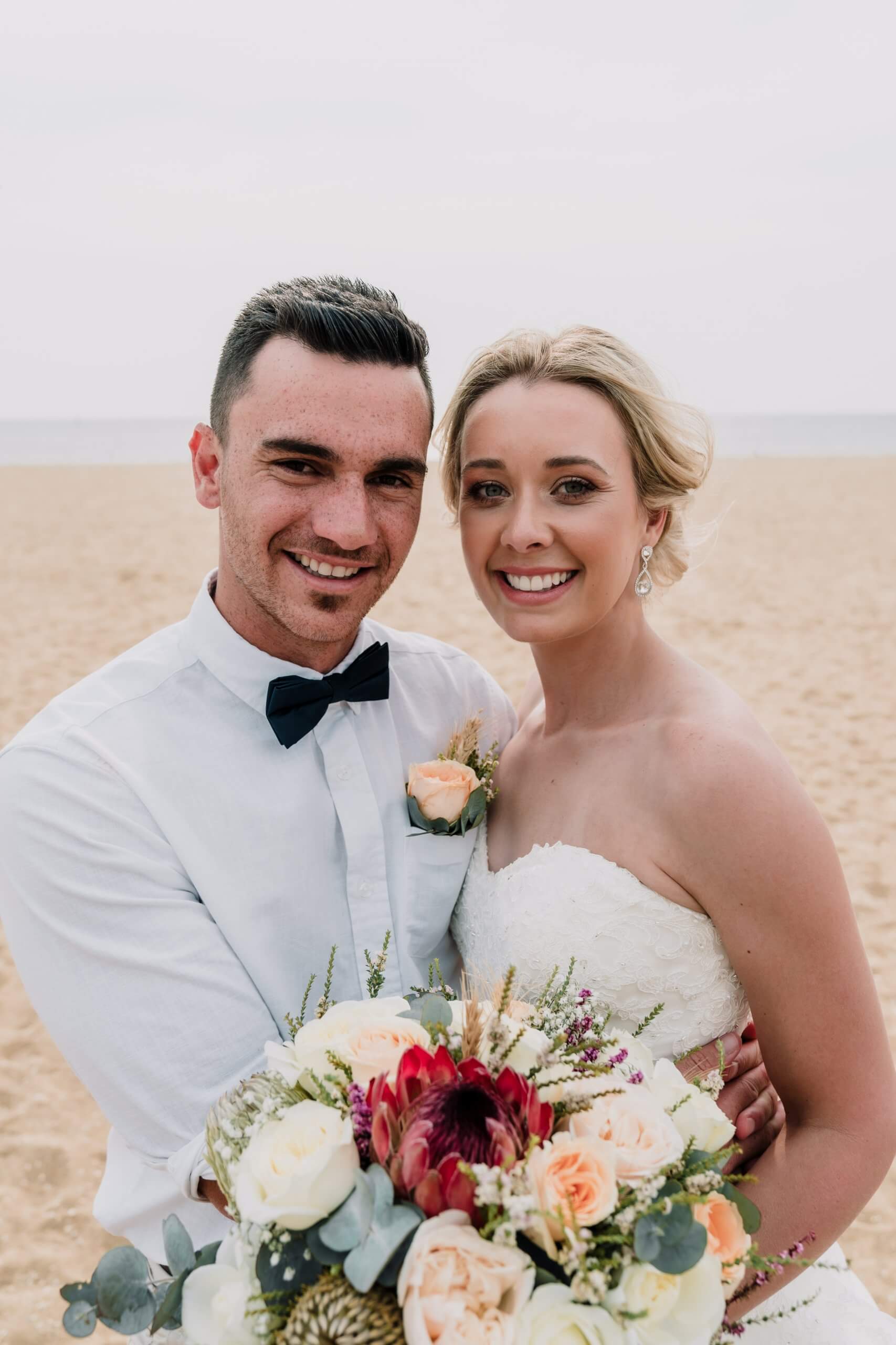 A lovely shot of the bride and groom happily smiling by the beach captured by Black Avenue Productions