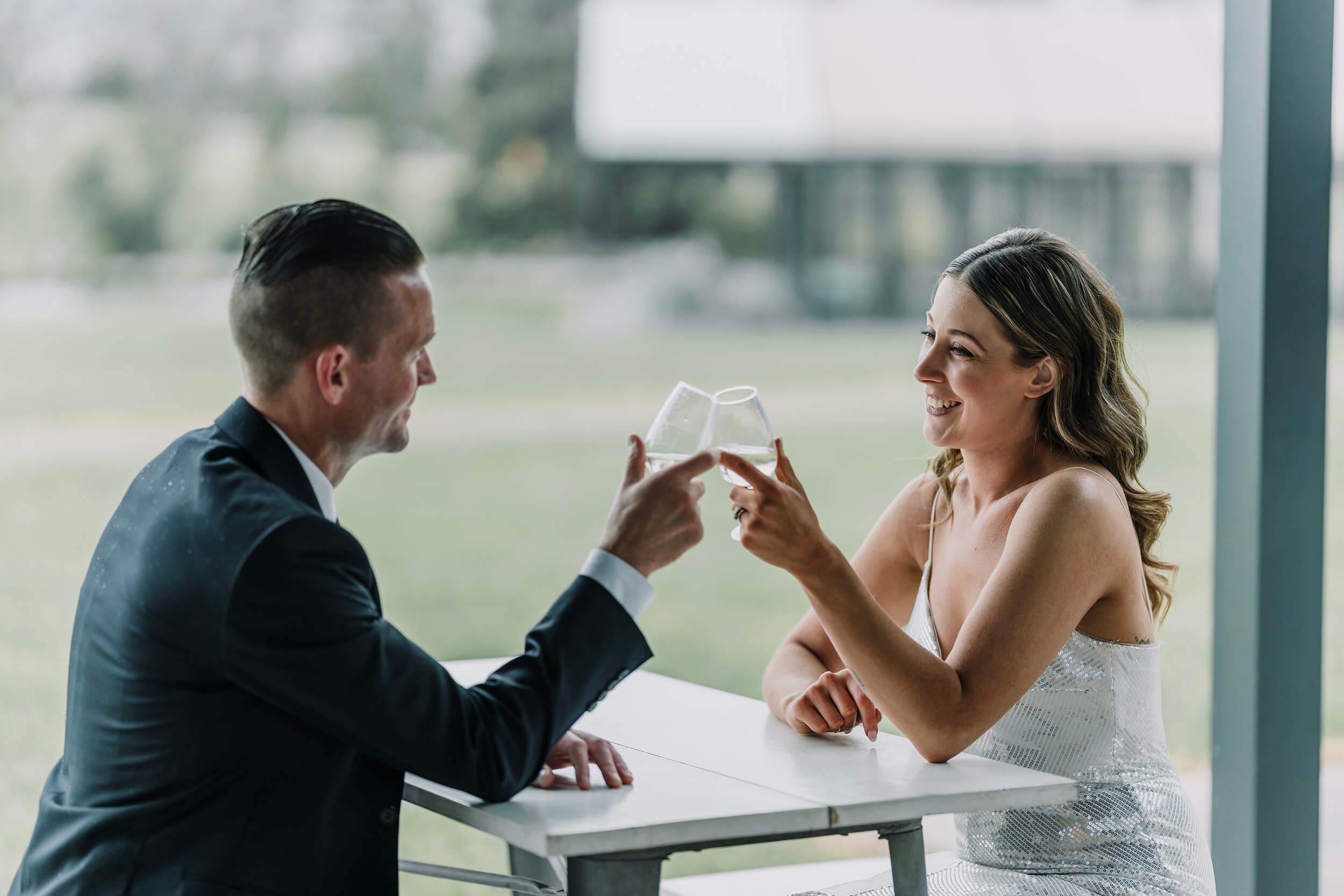 Newly Engaged Couple smiling as they hold a glass of wine, Captured by Black Avenue Productions