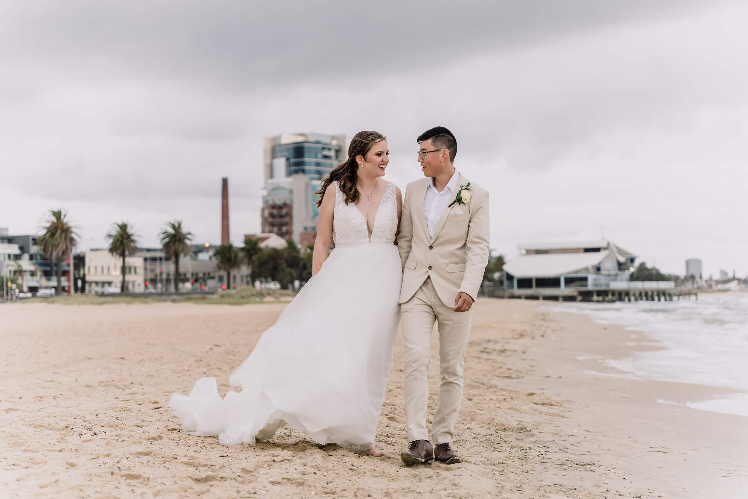 couple holding hands by the beach while the clouds start to roll in, captured by black avenue productions. Wedding Day Interrupted by bad weather