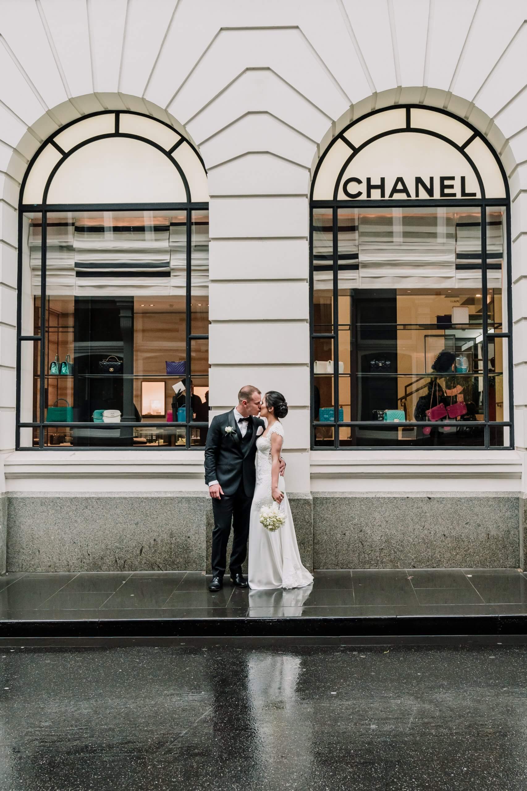 Wedding Shoot Interrupted by bad weather, bride and groom kissing by the wet street, captured by black avenue productions