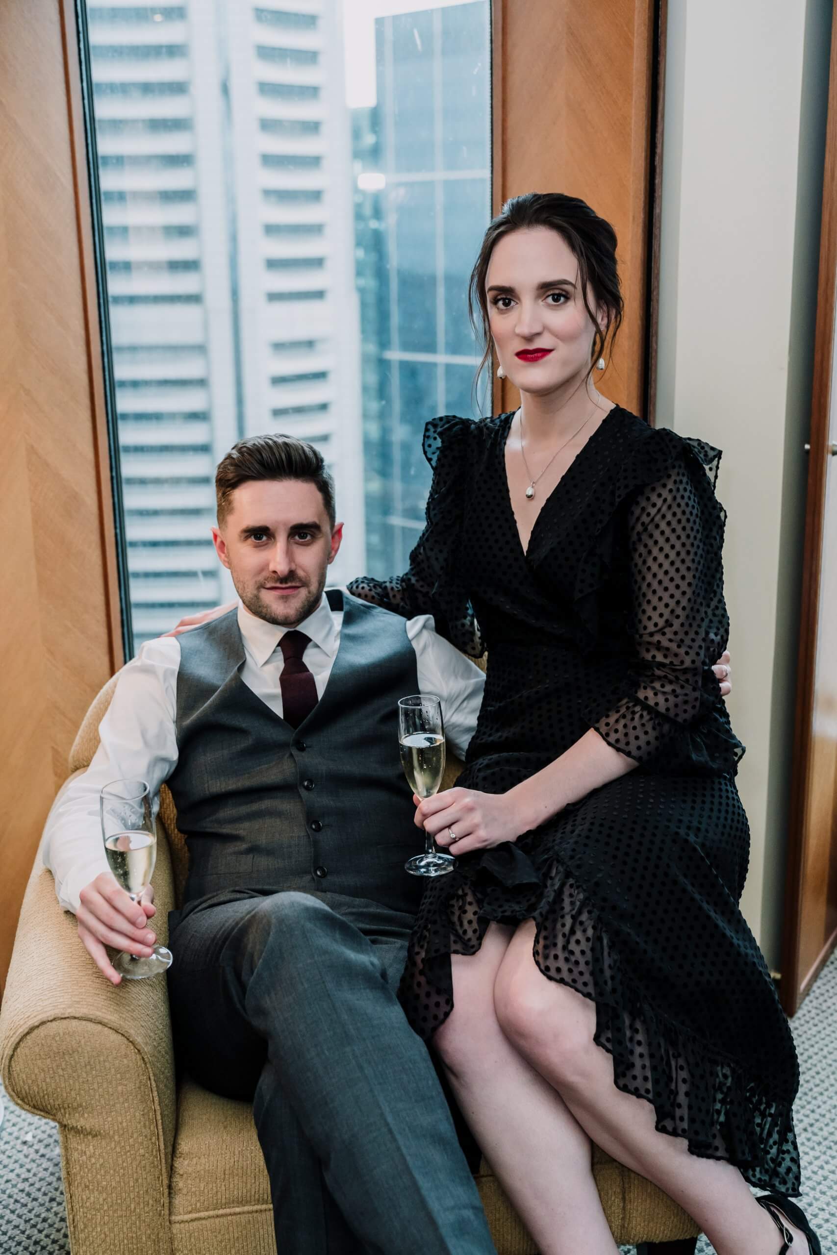 a sophisticated shot of the bride and groom sitting on a couch , captured by black avenue productions