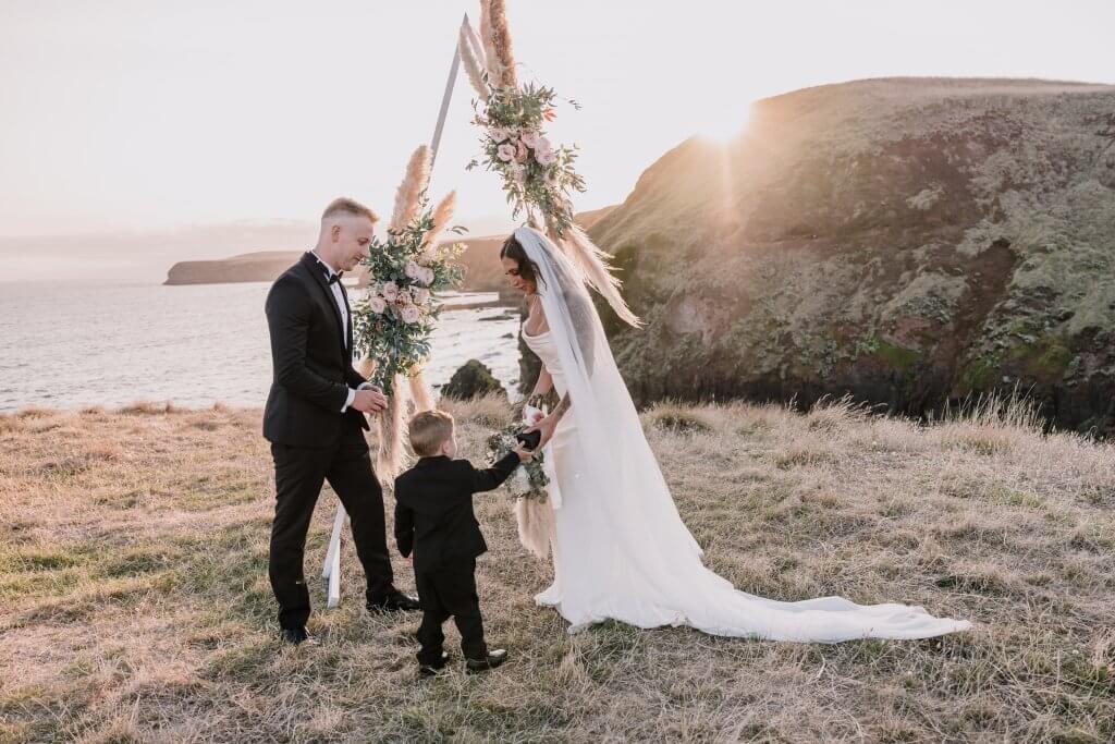 Planning An Intimate Wedding, a beautiful photo of the bride, the groom, and their son on top of a cliff while the sun is setting. Captured by Lowina Blackman of Black Avenue Productions