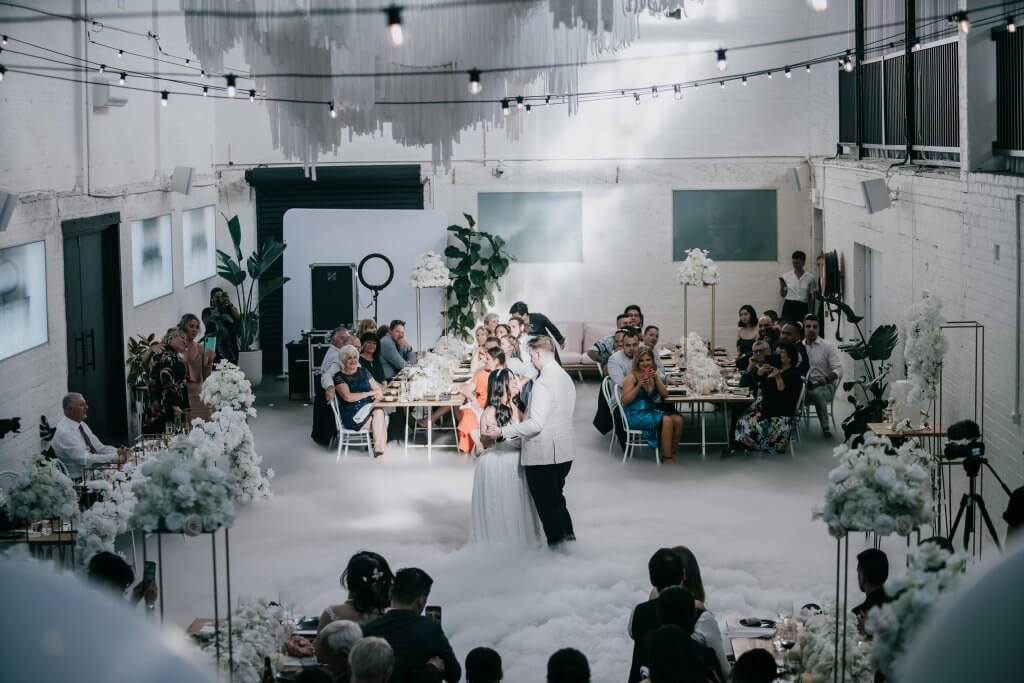 Planning An Intimate Wedding, bride and groom dancing in the middle of the room while a ray of sunlight acts as a spotlight to the newly wed couple. Captured by Derek Chan of Black Avenue Productions