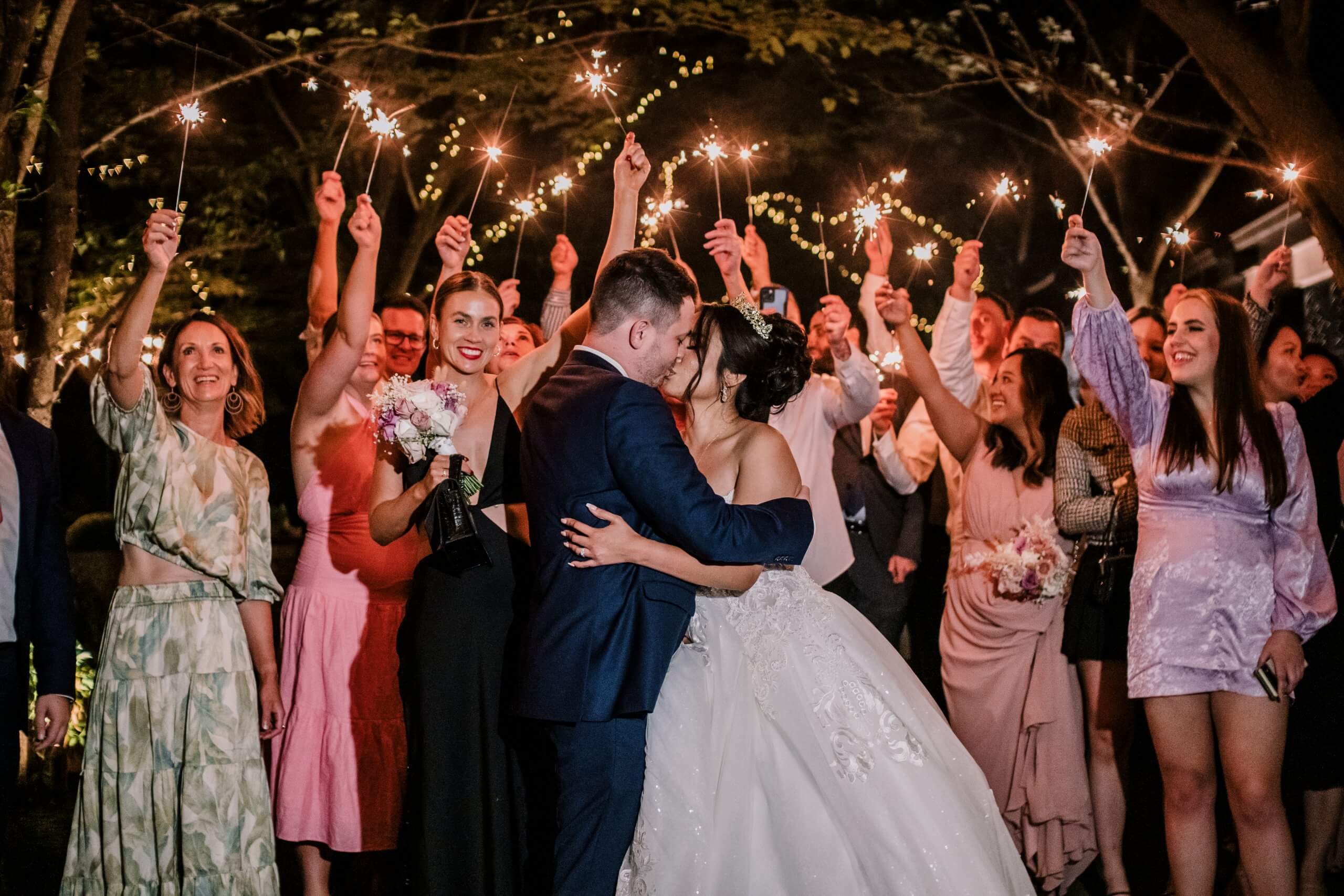 Planning An Intimate Wedding, bride and groom kissing while the guests are happily cheering and celebrating. Captured by Black Avenue Productions
