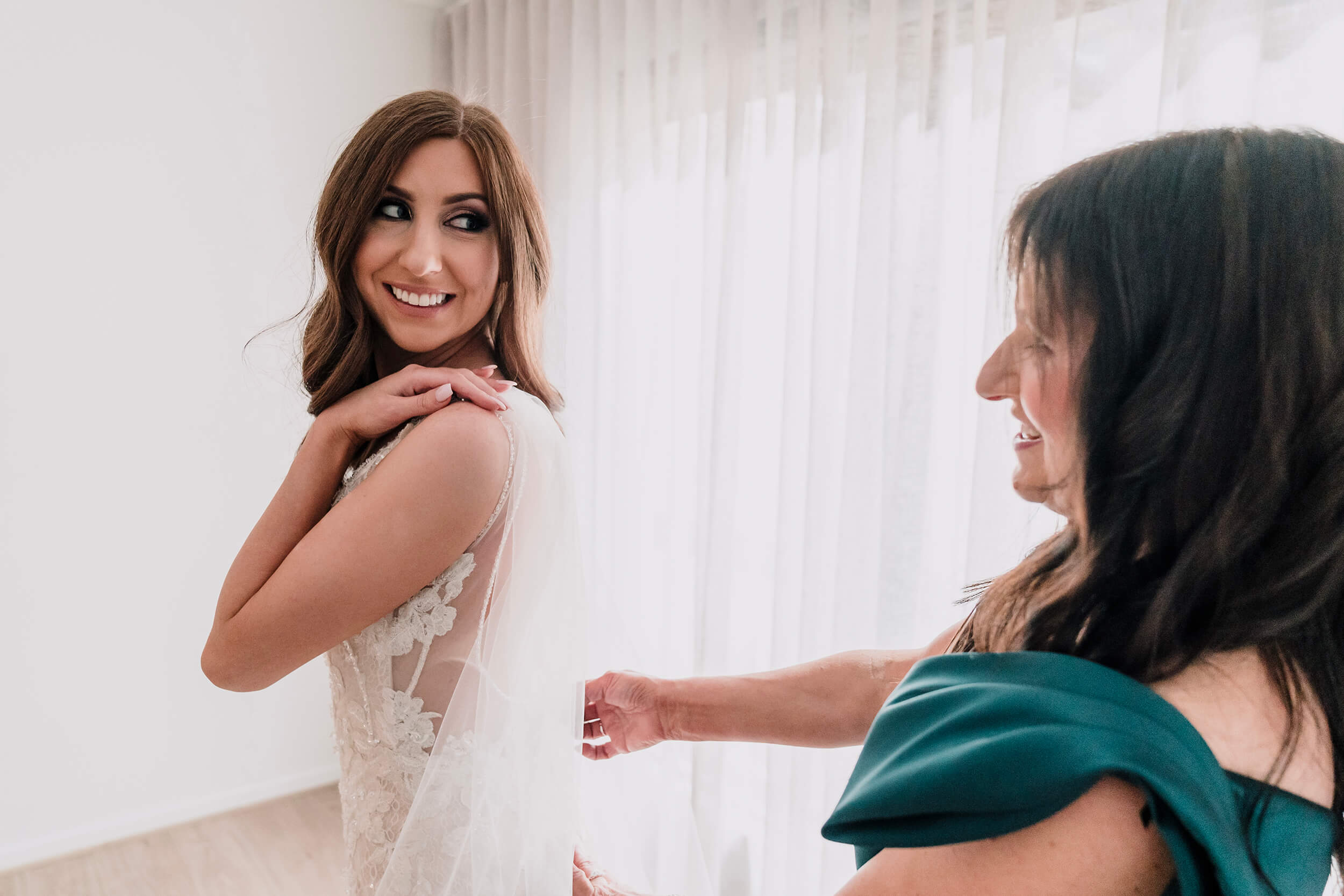 Engagement Shoot Preparations, helping the bride put on her wedding dress , captured by Black Avenue Productions