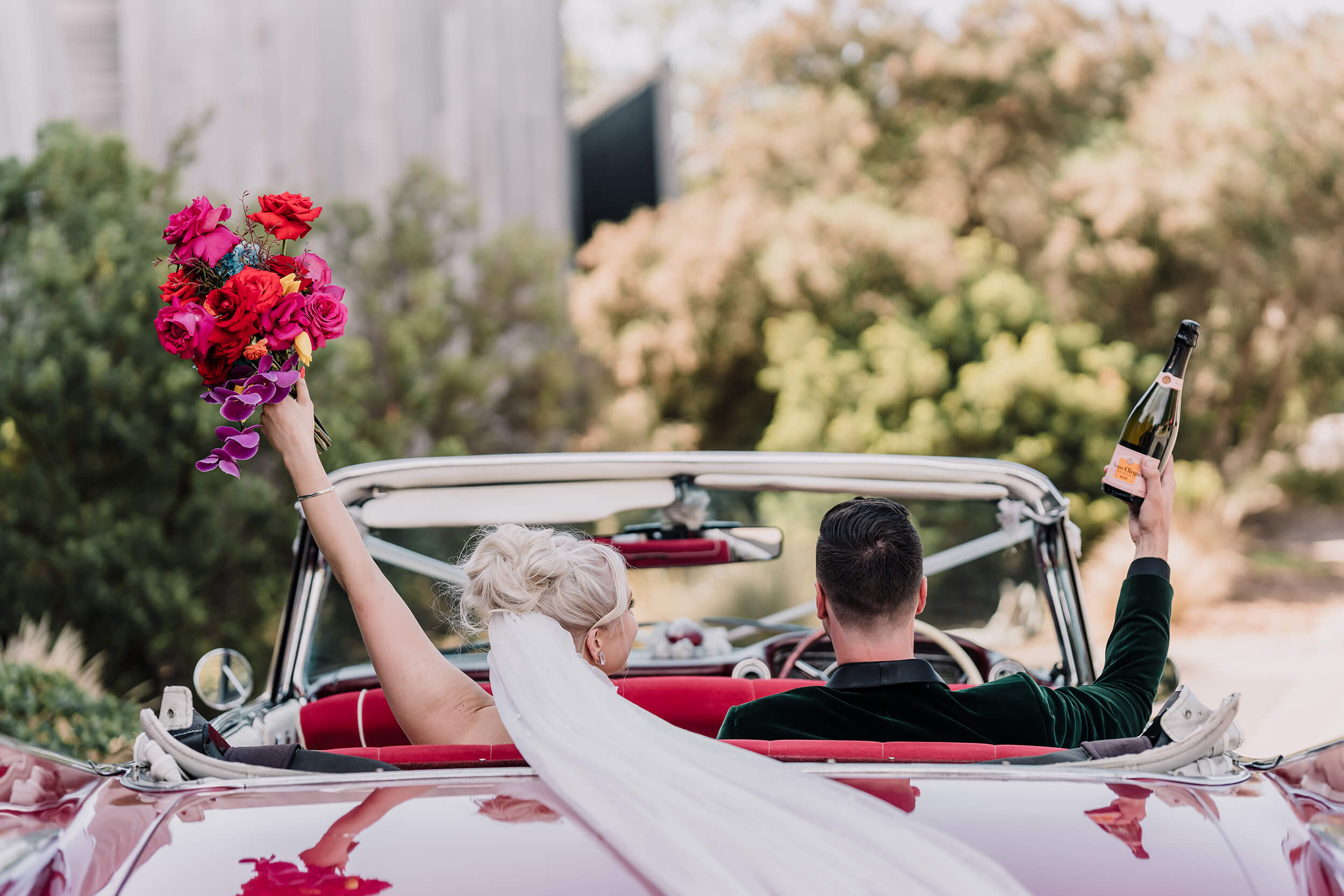 Get a wedding car, newly wed couple driving away in a red convertible Cadillac, captured by Black Avenue Productions