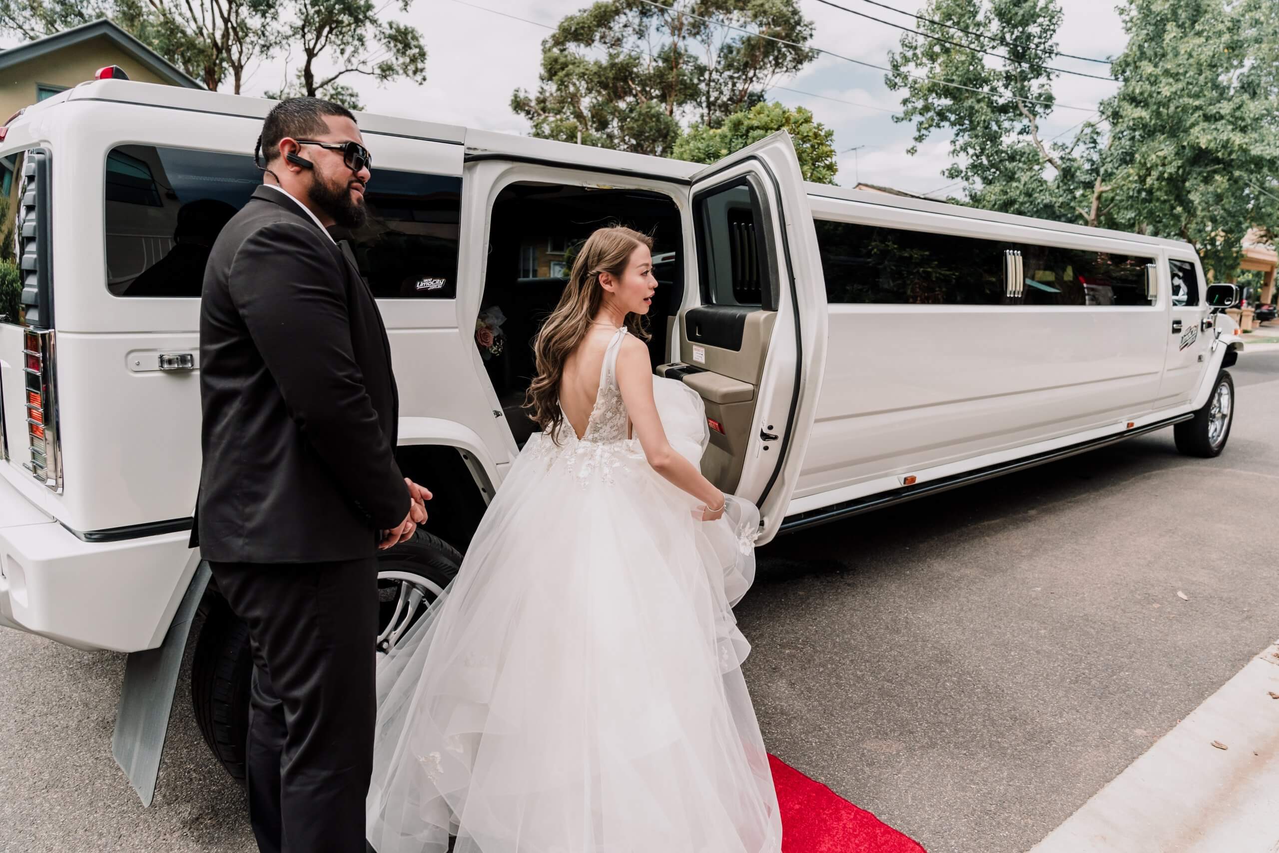 Get a wedding car, bride walks down a hummer limousine with a red carpet. captured by Black Avenue Productions