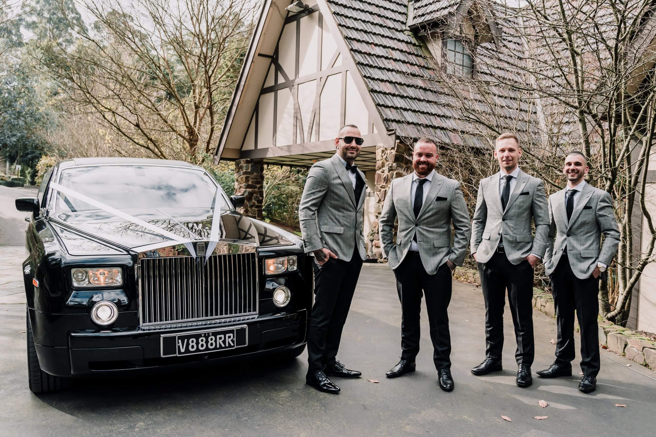 The groom with his groomsmen posing beside a black limousine. Captured by Black Avenue Productions