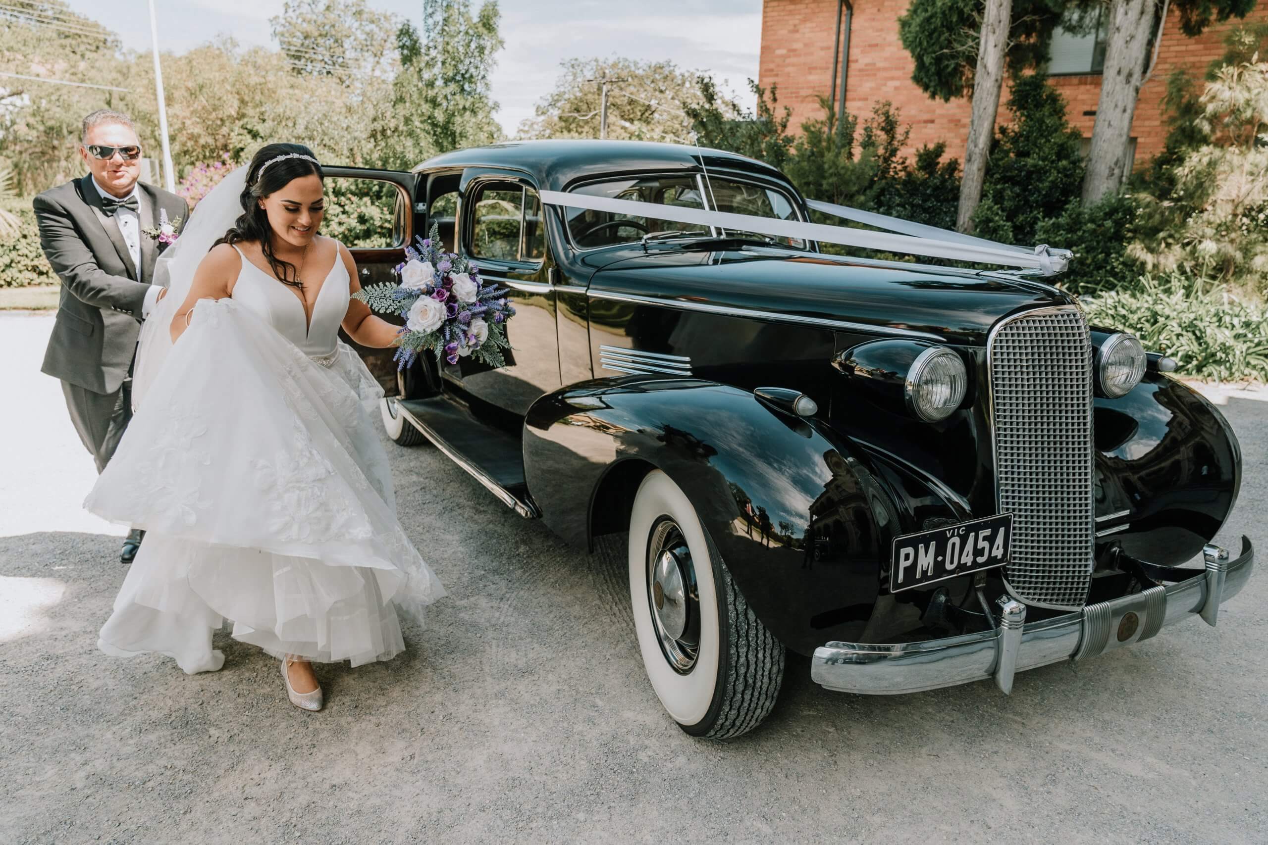 Get a wedding car, lovely bride walks beside a vintage cadillac wedding car, captured by Black Avenue Productions