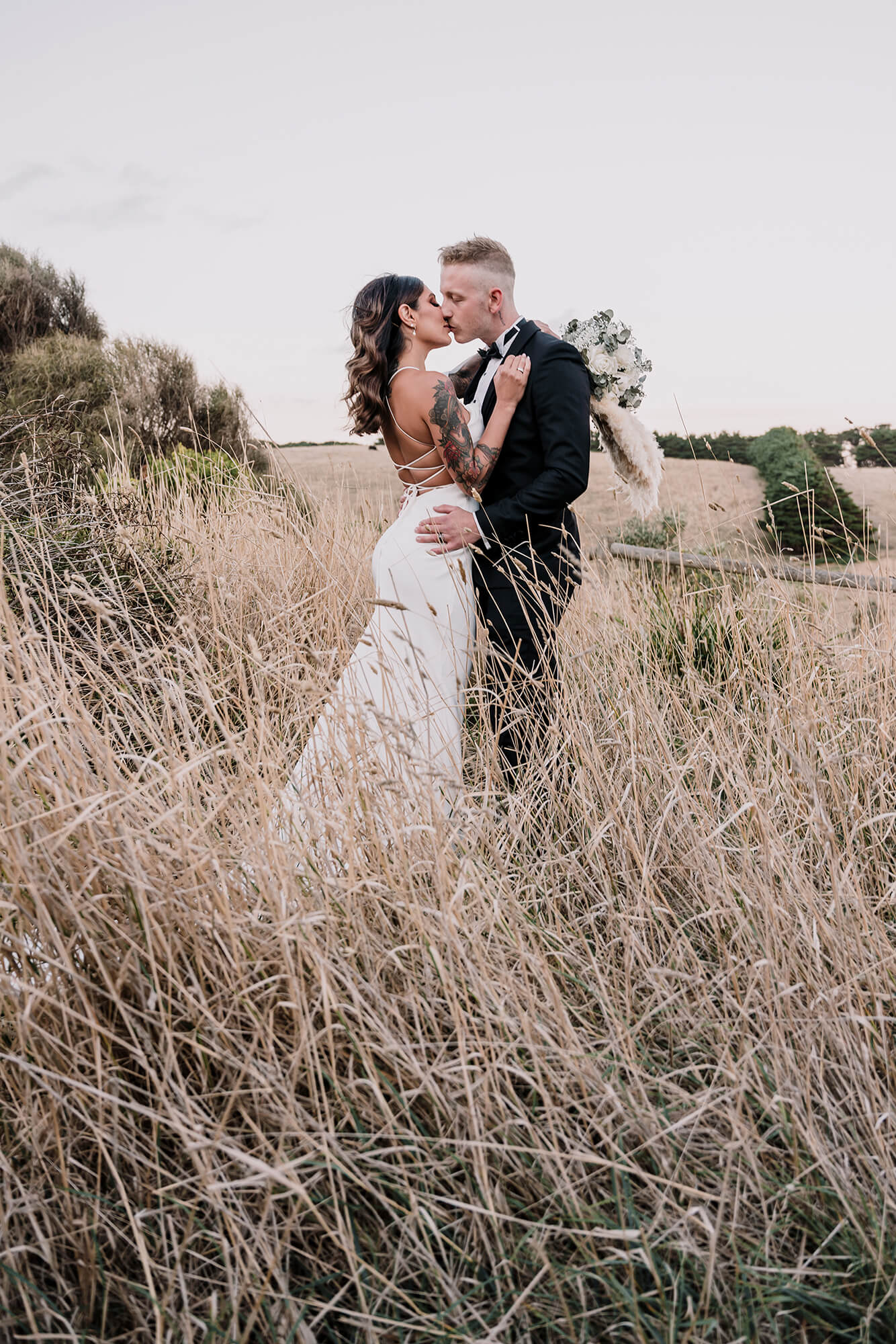 beautiful shot of the bride and groom kissing by the grass, captured by Black Avenue Productions