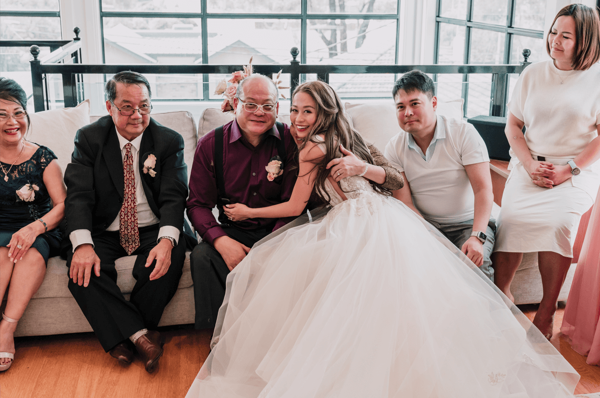 The bride is happily embracing her parents as they are surrounded by other family members.