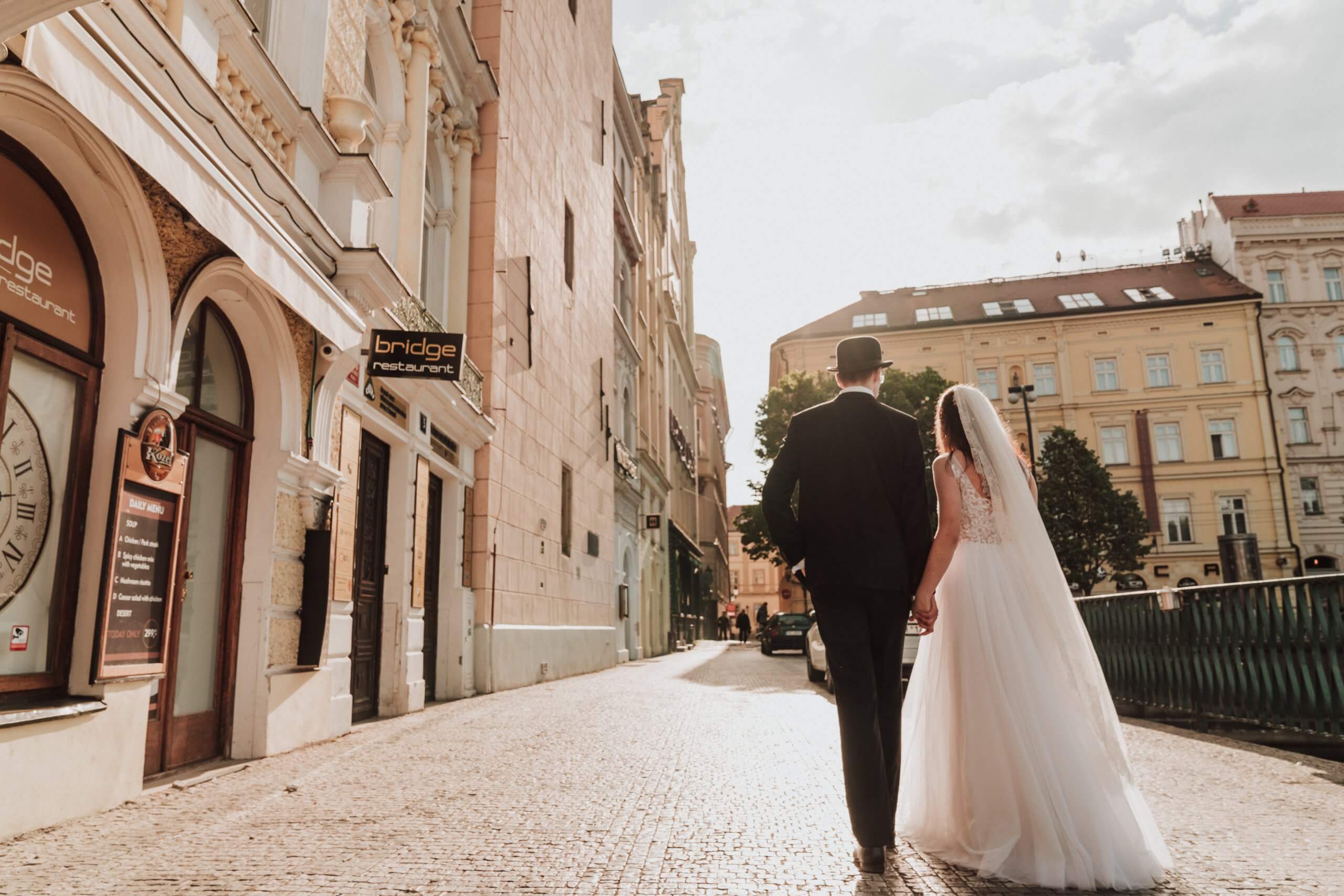 Bride and groom, hand in hand walks the streets of Prague.