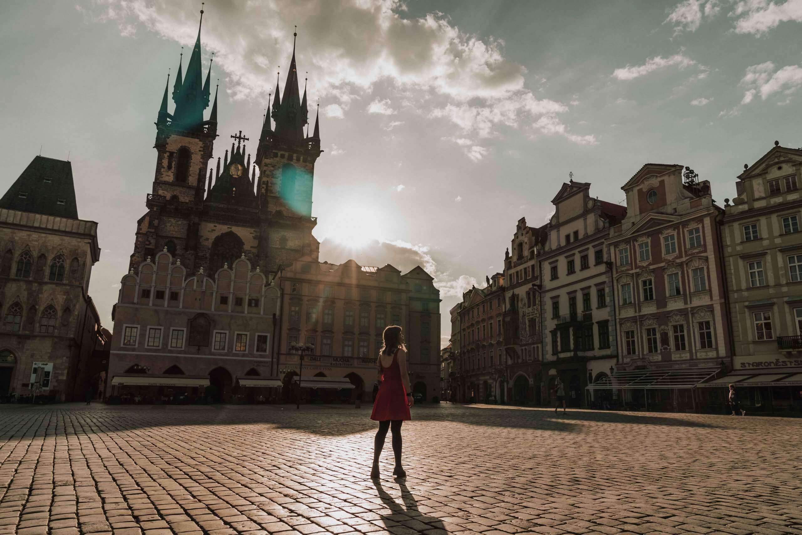 Female photographer stands under the soft sunlight in Prague's Old Town Square.