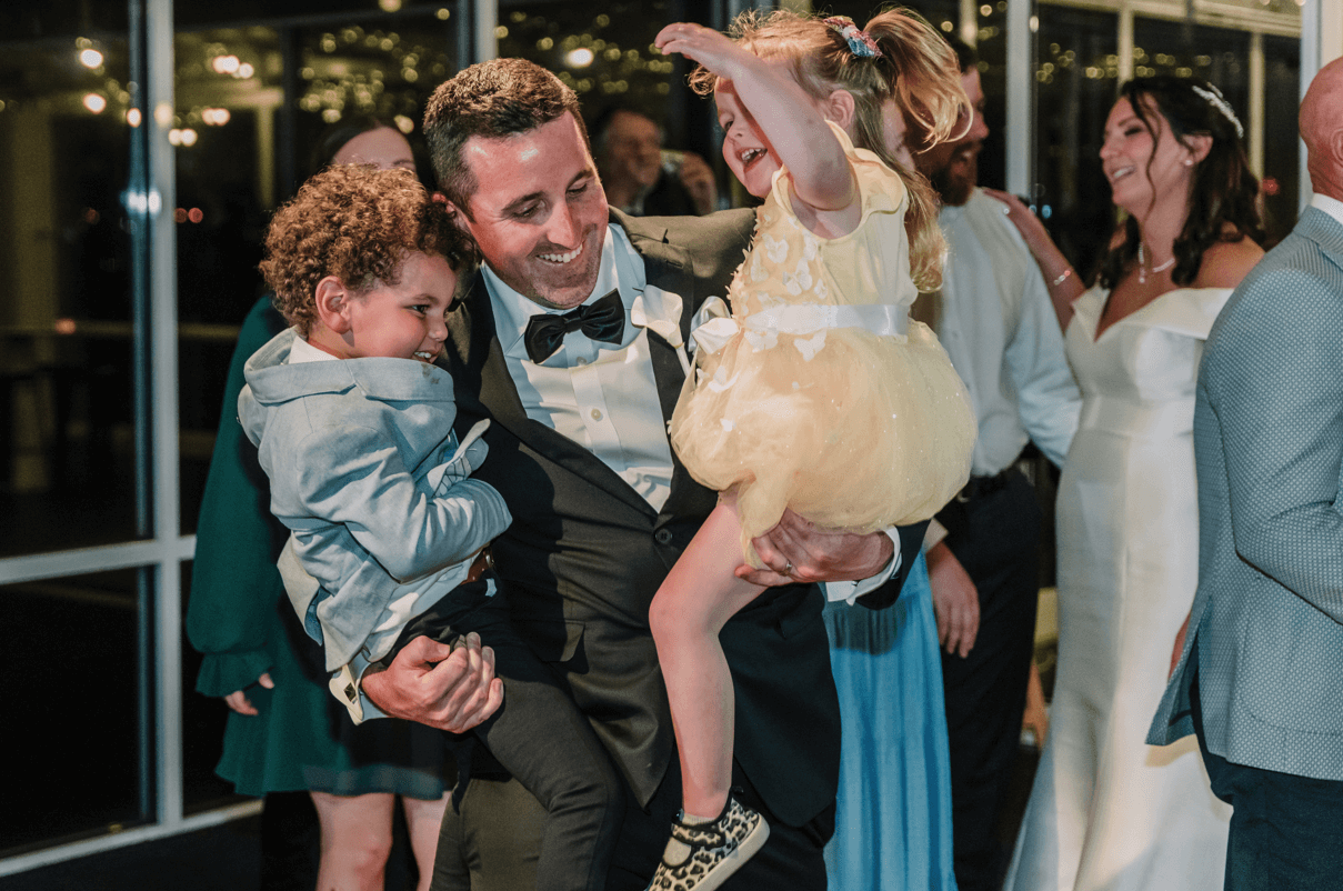 Grooms man carrying his nephews and dancing with them at the reception