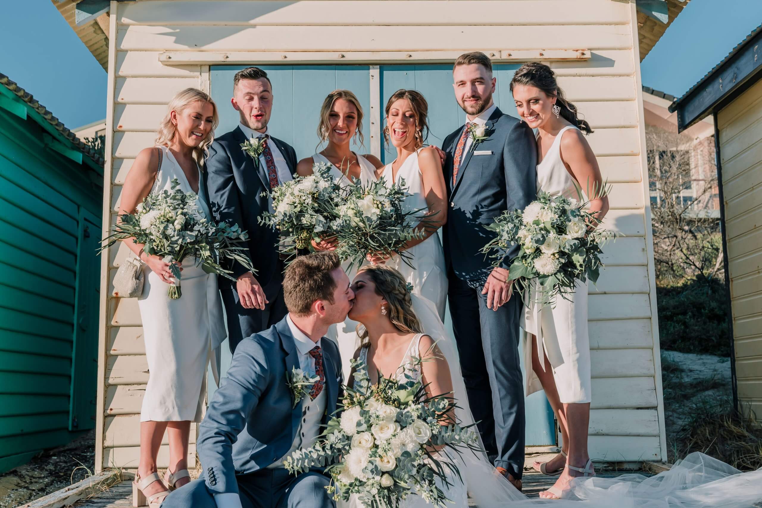 With their bridal party behind them, the newlywed shares a sweet kiss.