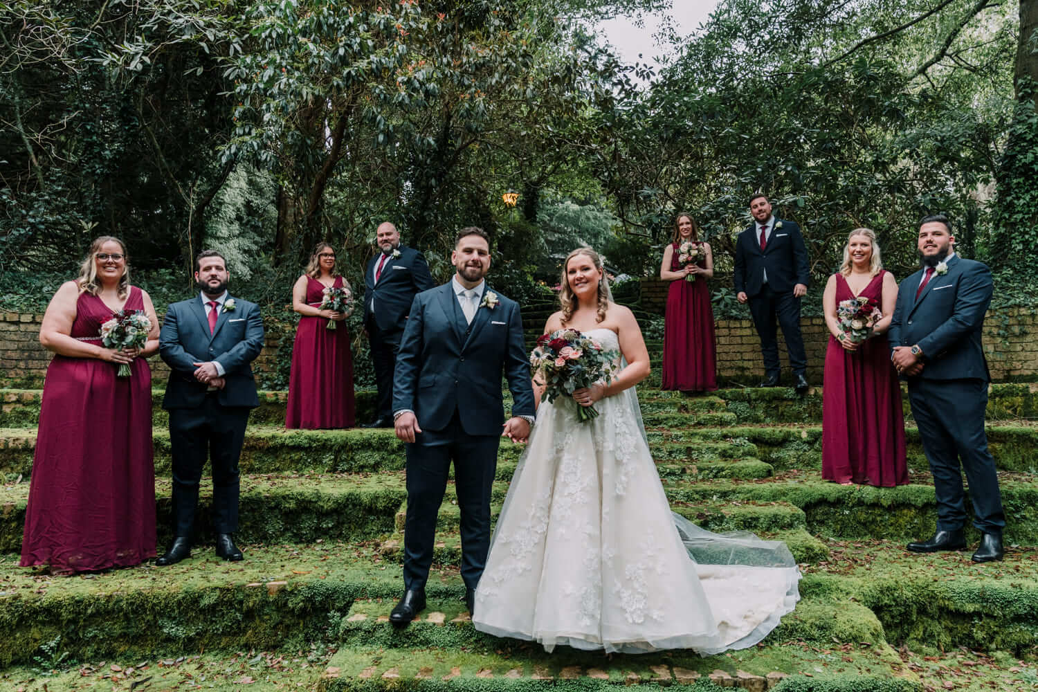 The bridesmaids are wearing burgundy dresses while the groomsmen wears matching ties