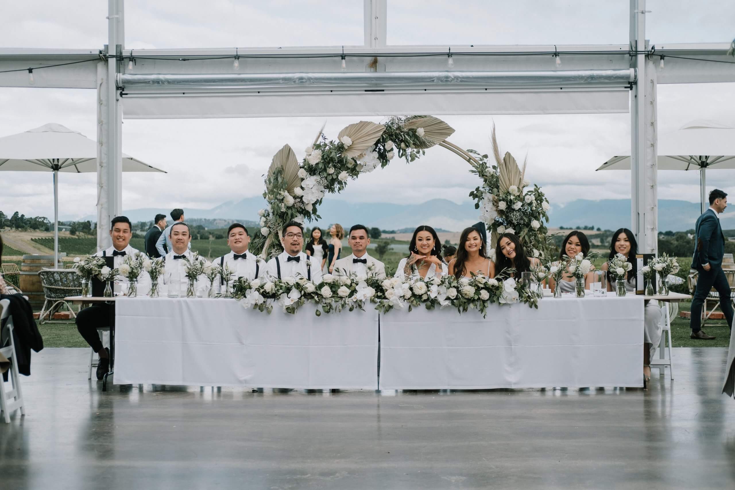 With an open venue for the reception, and the beautiful winery as the background, the bridal party smiles for the camera