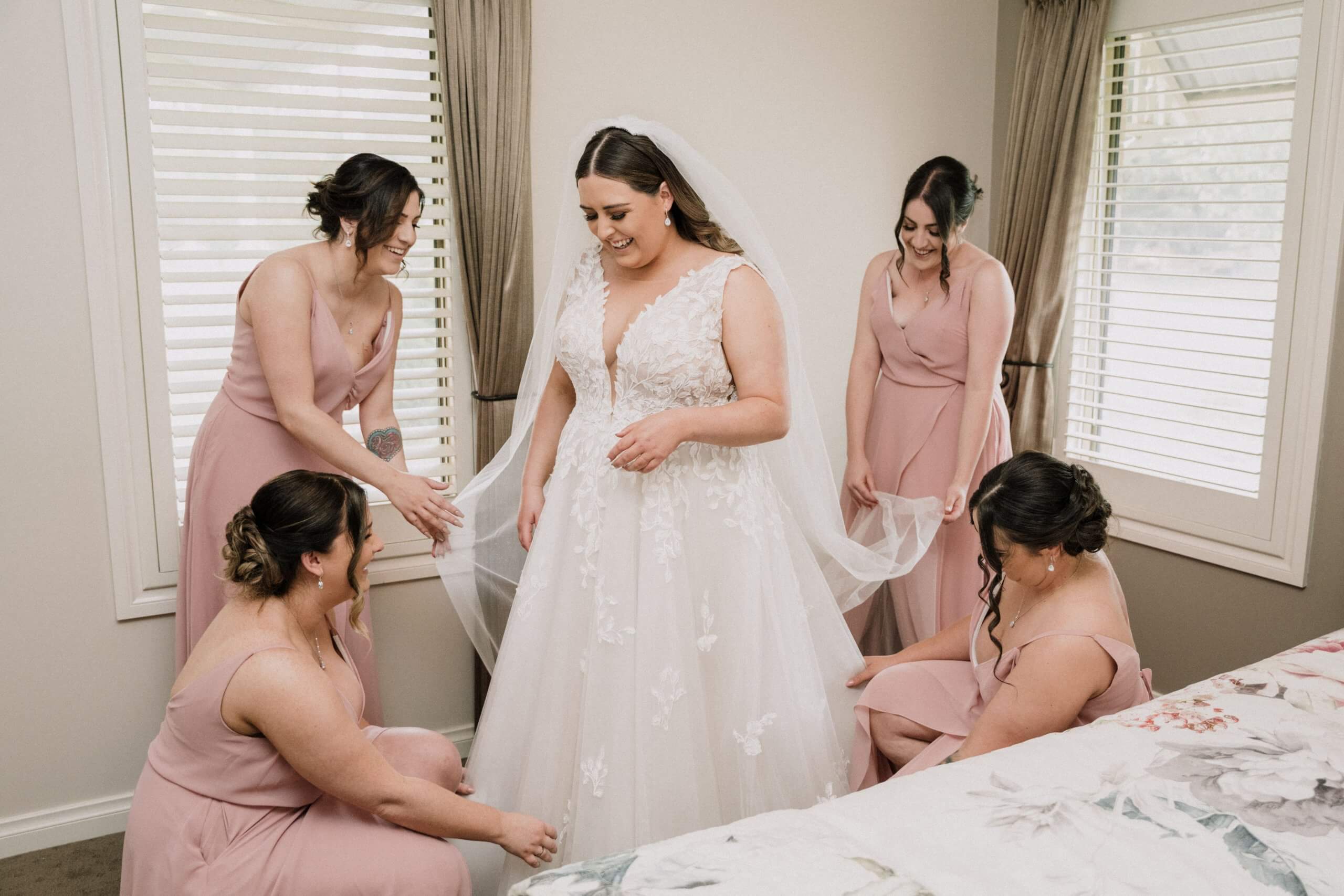 Four bridesmaids assists the bride in getting ready.