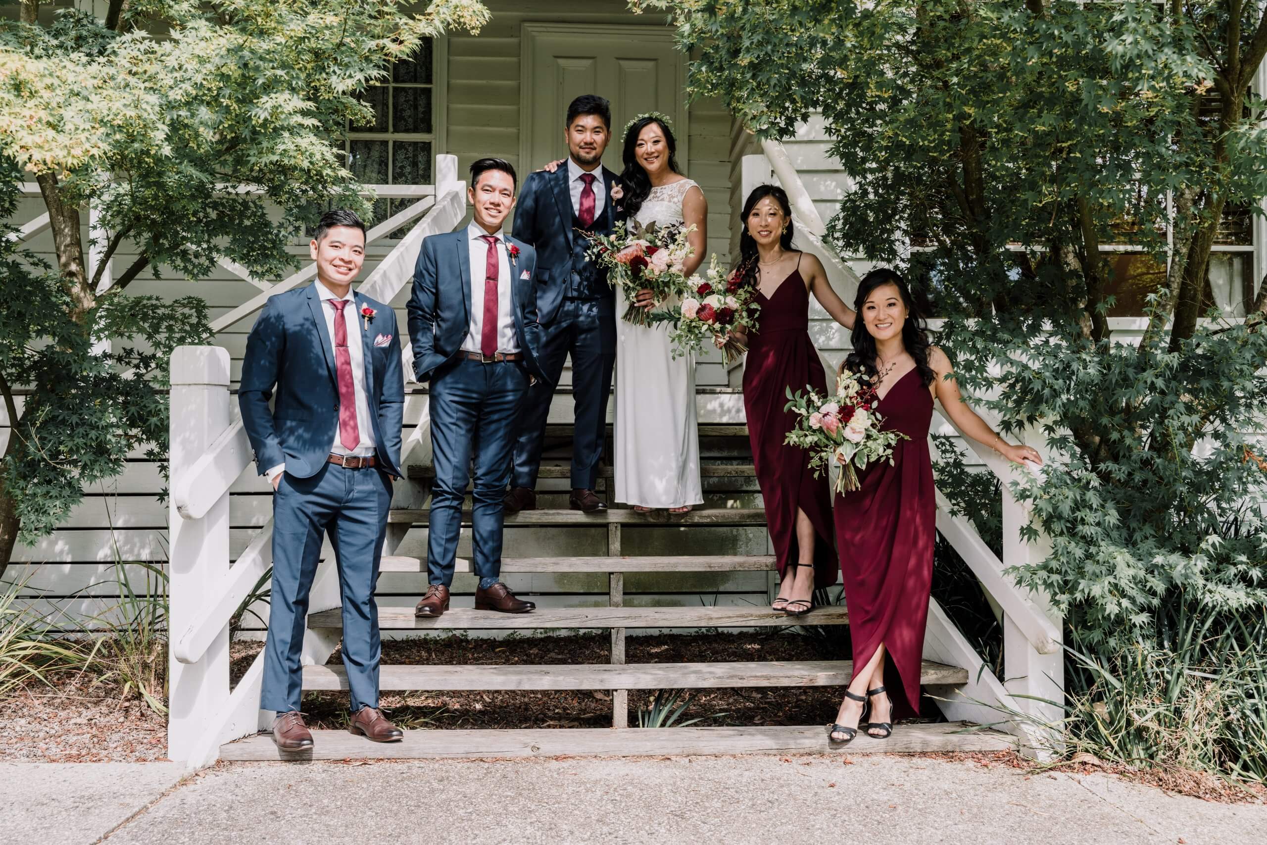 A photo of the bride and groom with two of their bridesmaids and groomsmen who are wearing magenta dresses for the ladies and matching magenta ties for the men.