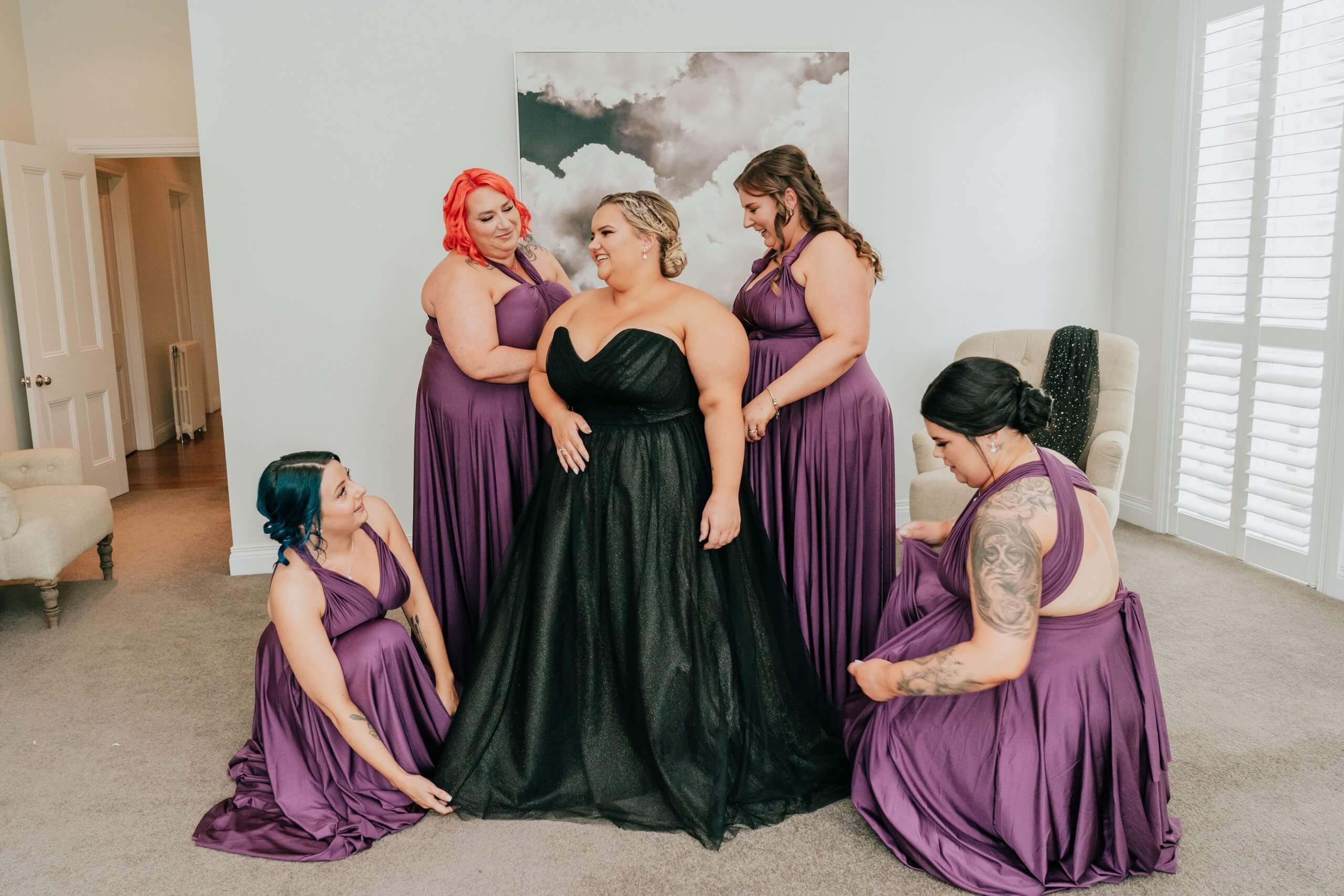 Bride in her unconventional black wedding dress, surrounded by her four bridesmaids who are wearing purple dresses.