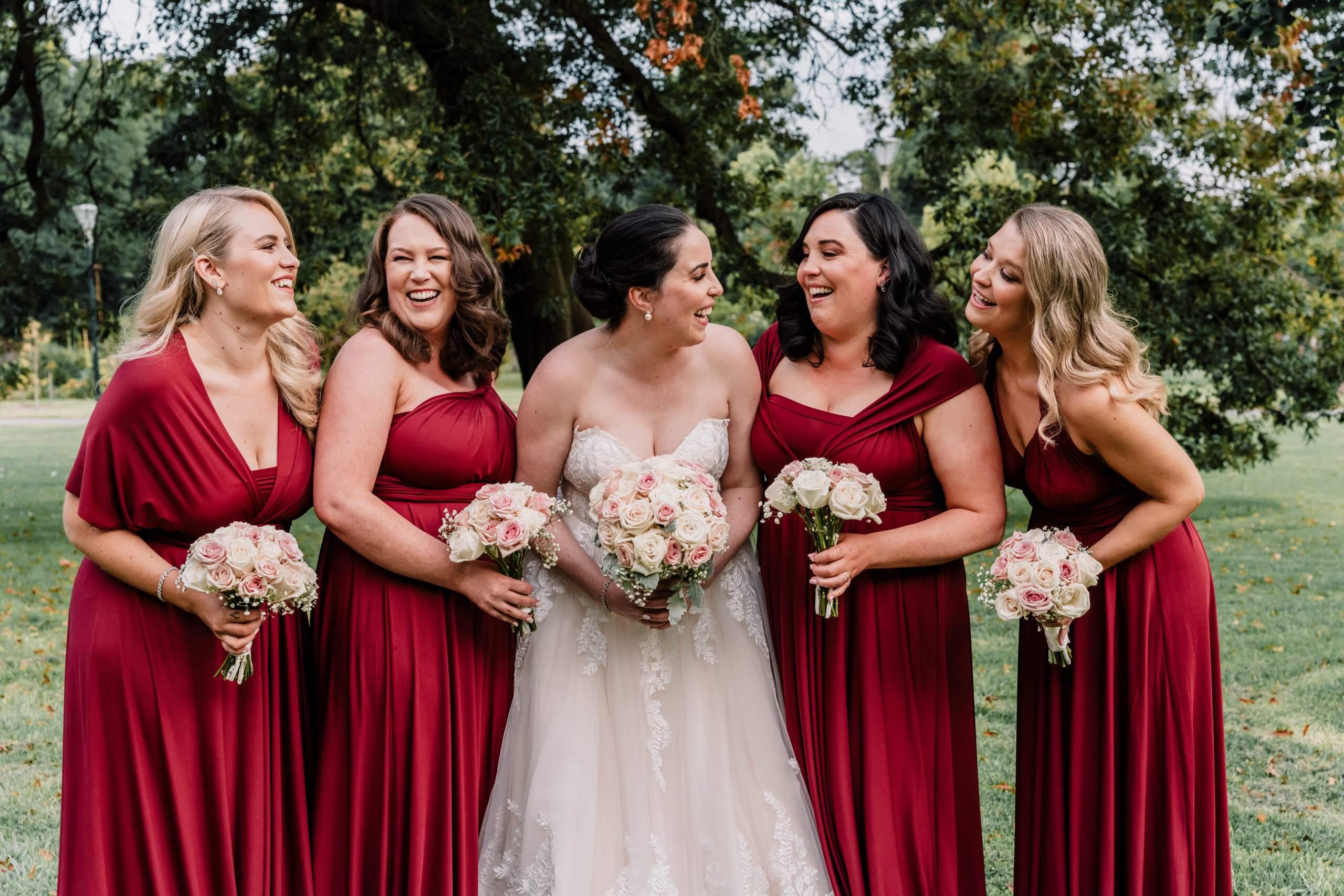 Beautiful candid shot of a bride and her four magenta-dressed bridesmaids.