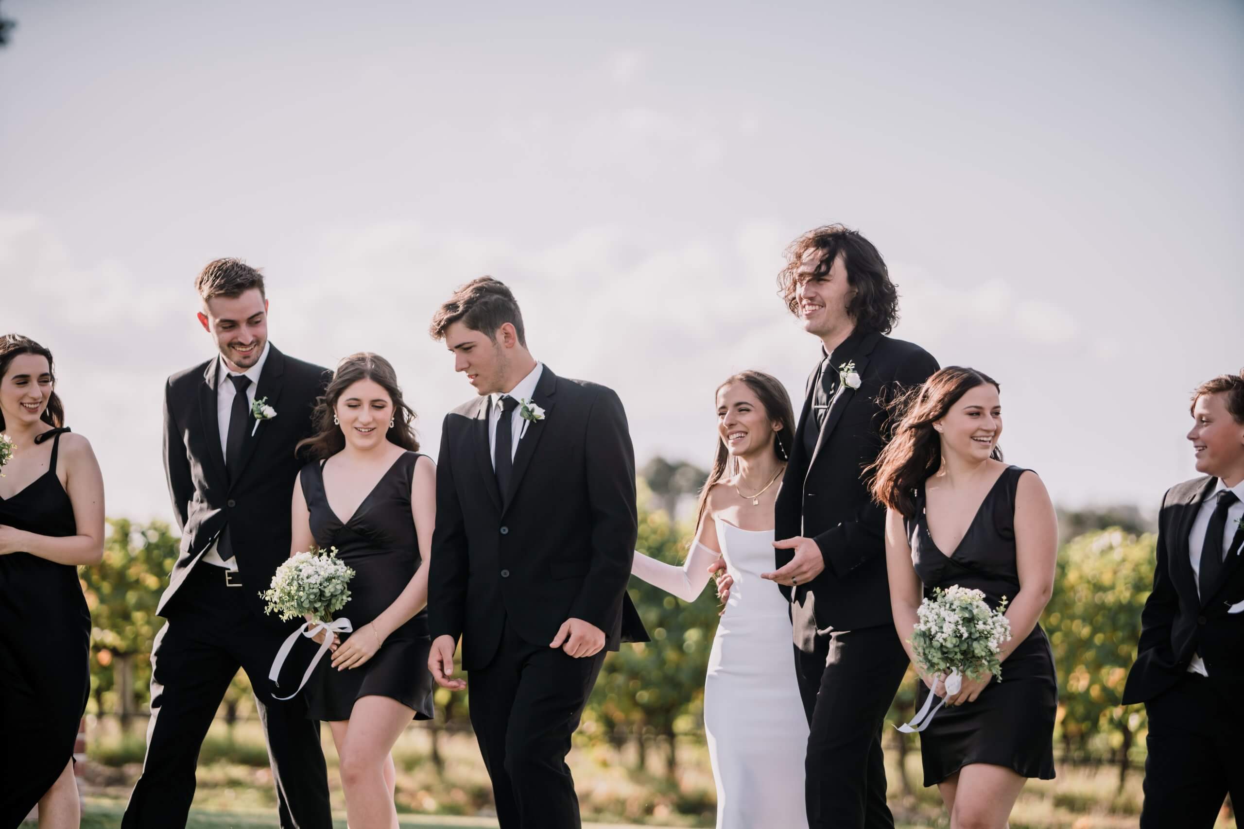 The bridal party, clad in black - with the exception of the bride - walks in the middle of a clearing.