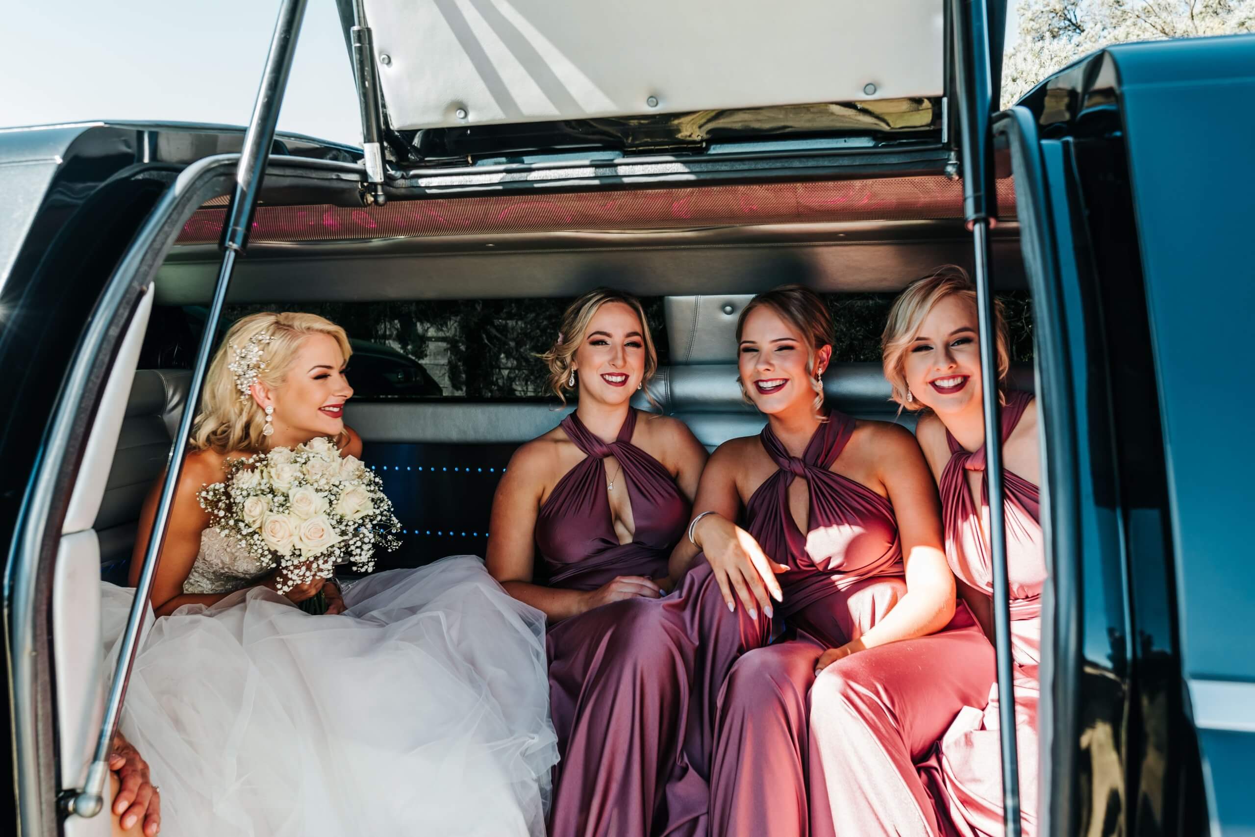 The beautiful bride and her bridesmaids sitting inside the limo, ready to head out to the ceremony venue.