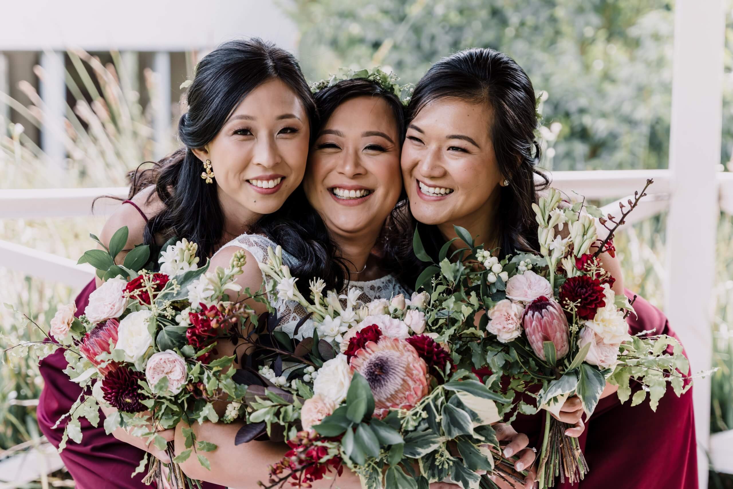 Lovely photo of the bride and her bridesmaids while holding colorful bouquets of protea and peonies.