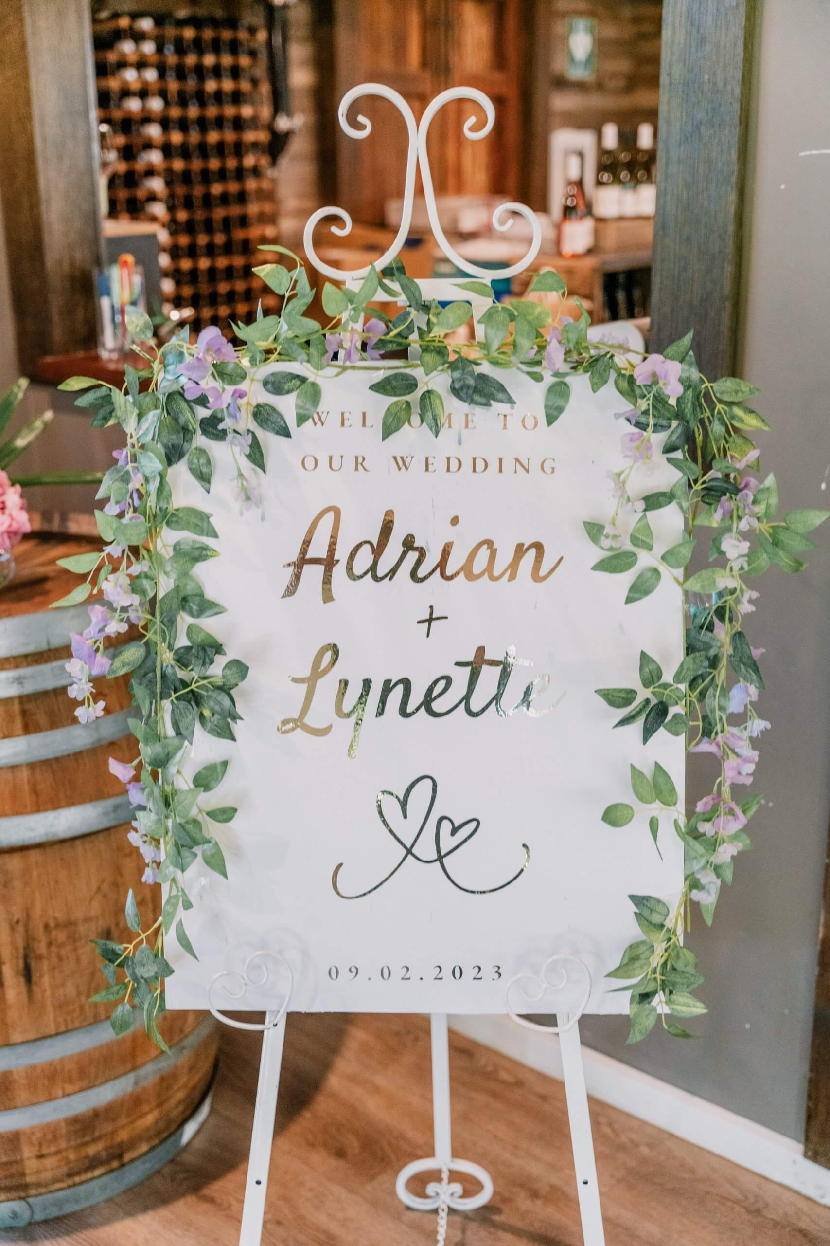 Welcome wedding signage adorned with purple and white flowers.