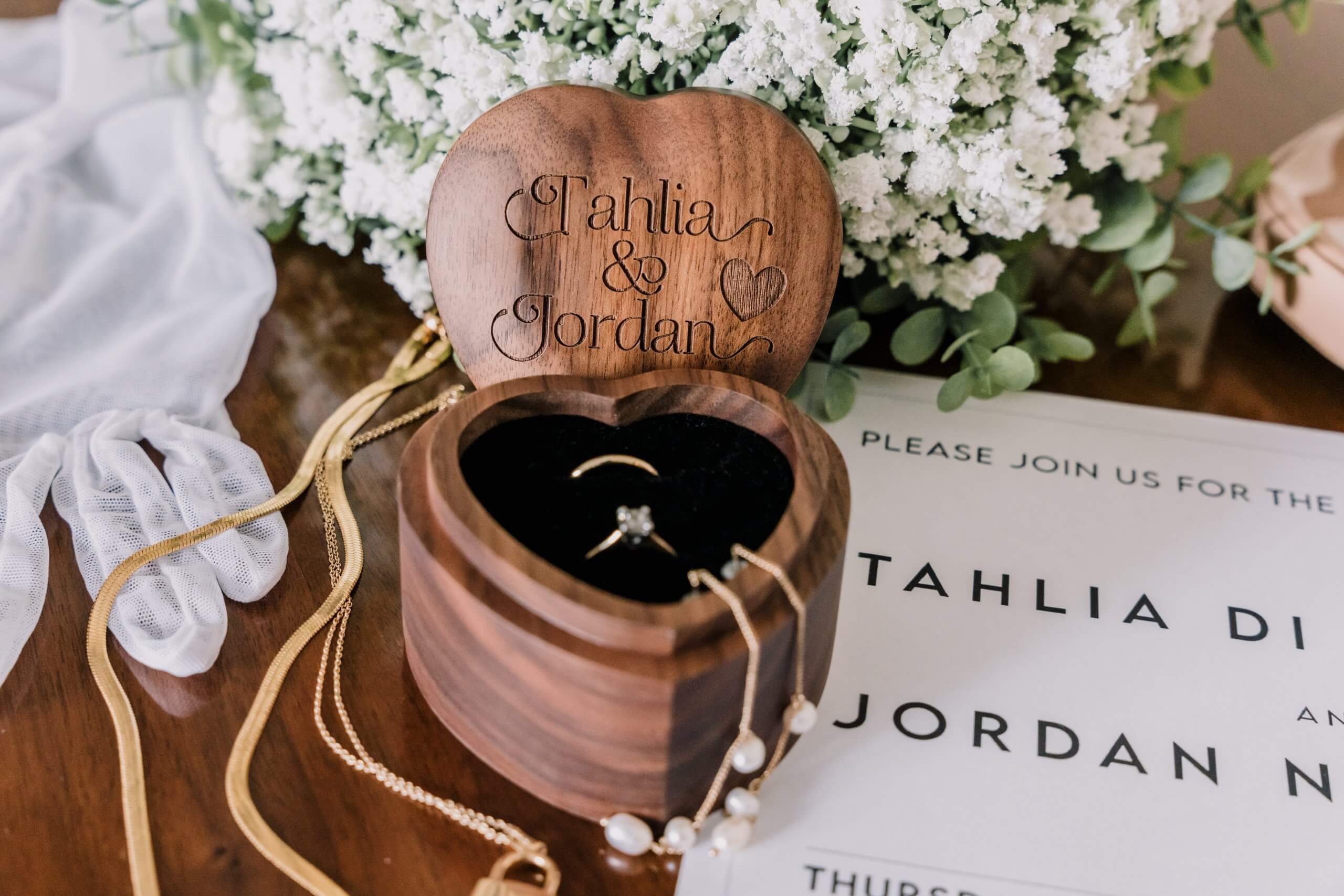 Wedding details - a wooden ring box, accessories, white babies breath, wedding invitation and white lace gloves.